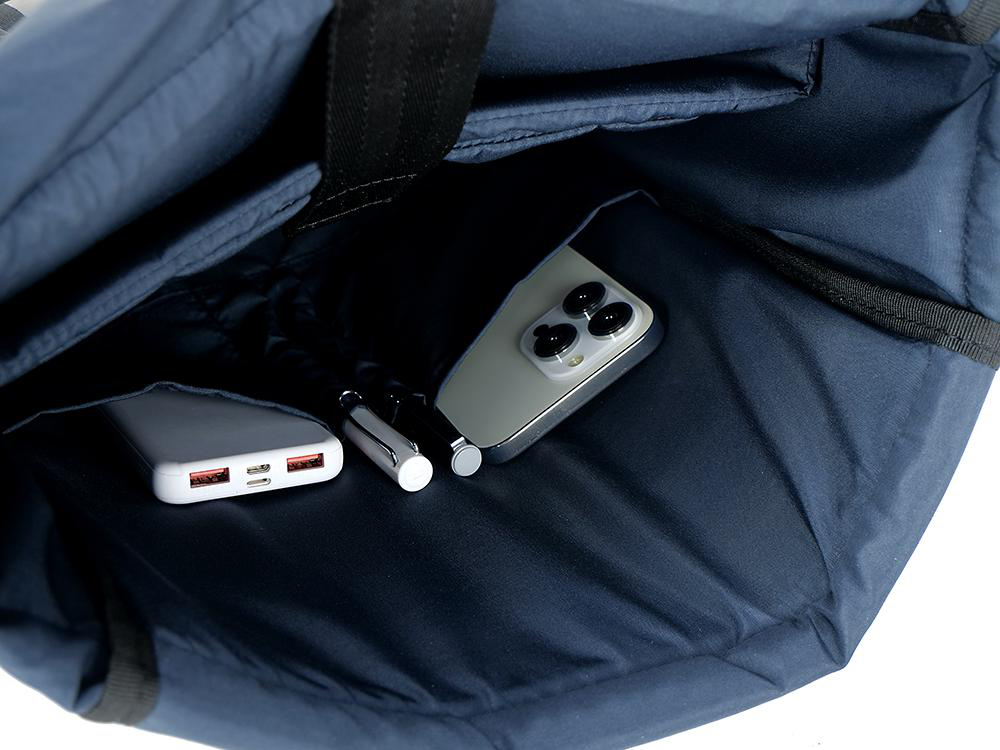 In einer marineblauen Tragetasche sind ein Telefon, ein Stift und eine Powerbank sichtbar.