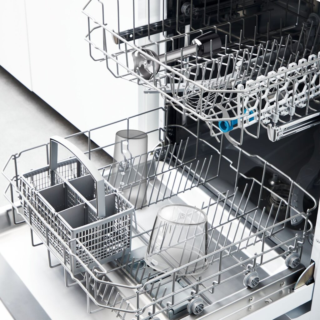 Wnętrze zmywarki z górnym i dolnym koszem. Szklanki i naczynia znajdują się w koszach.