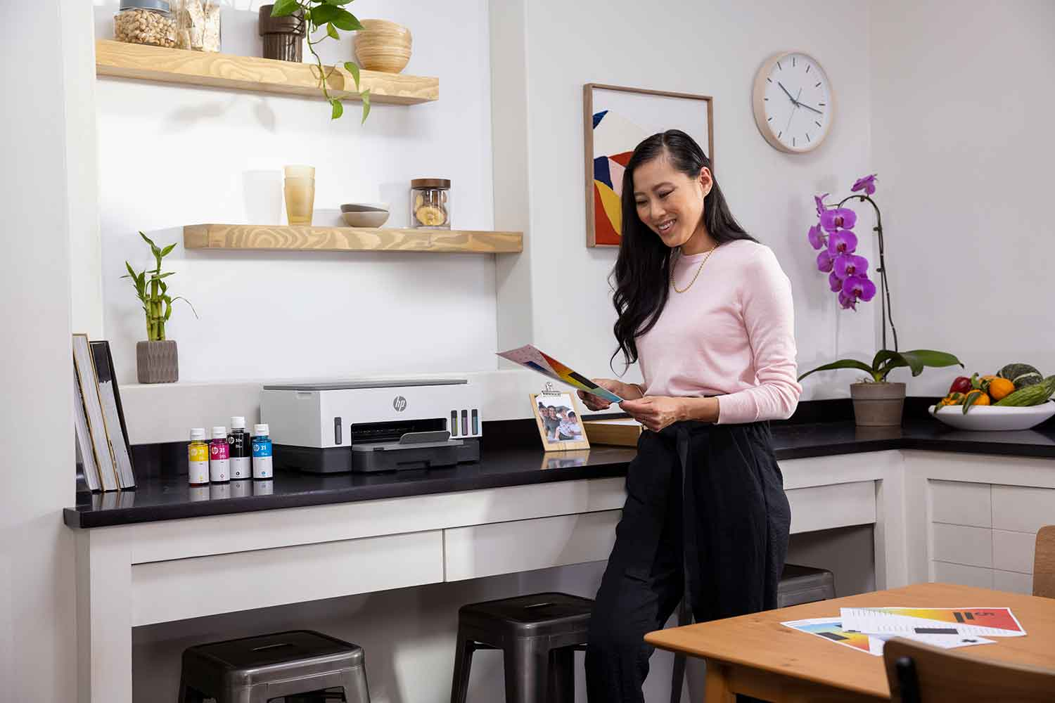 Een vrouw staat aan een aanrecht met bedrukt papier naast een printer.