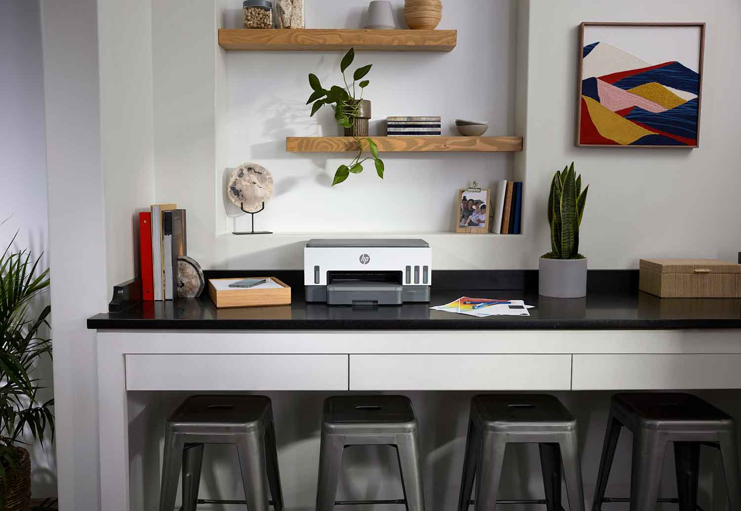 Een printer op een bureau met een witte en grijze behuizing, zwart oppervlak en houten planken op de achtergrond.