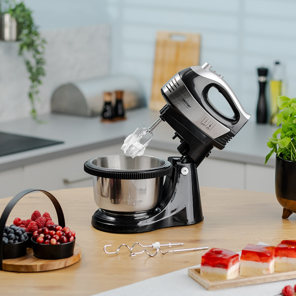 Czarny i srebrny mikser stojący z misą i składnikami na stole. Kuchnia.