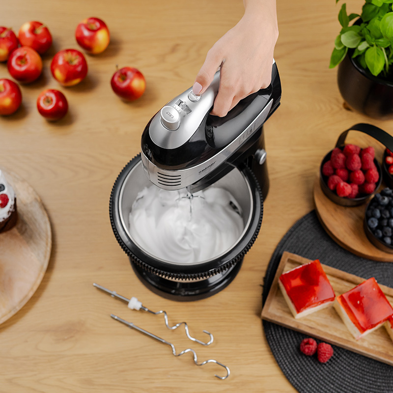 Mikser ręczny w użyciu. Miesza coś w misce, z bliskimi składnikami.