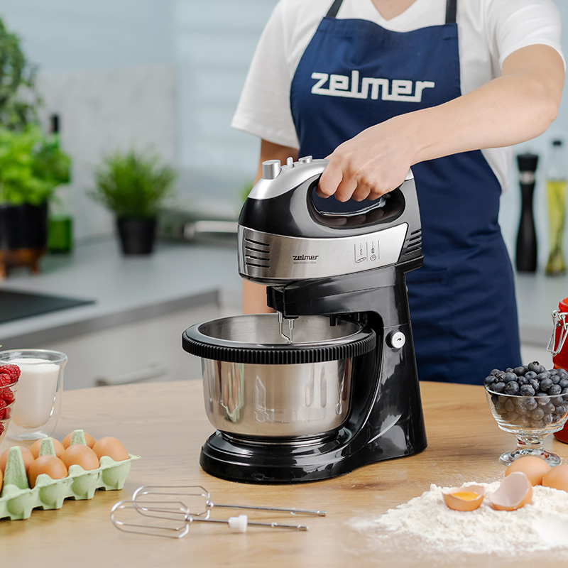 Czarny i srebrny mikser z misą, obsługiwany przez osobę.