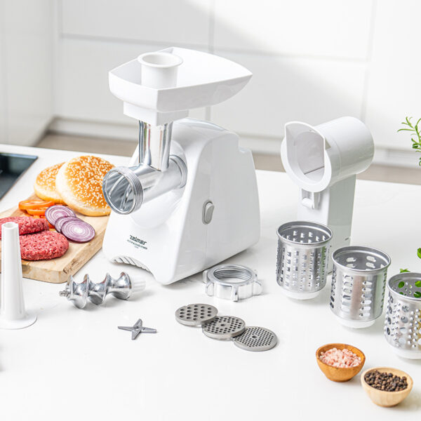 Biała maszynka do mięsa z akcesoriami. Zawiera burgery, bułki, cebulę i pietruszkę. Biała powierzchnia.