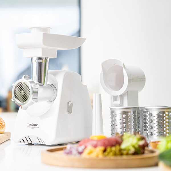 Biała maszynka do mielenia mięsa i akcesoria na białej powierzchni.