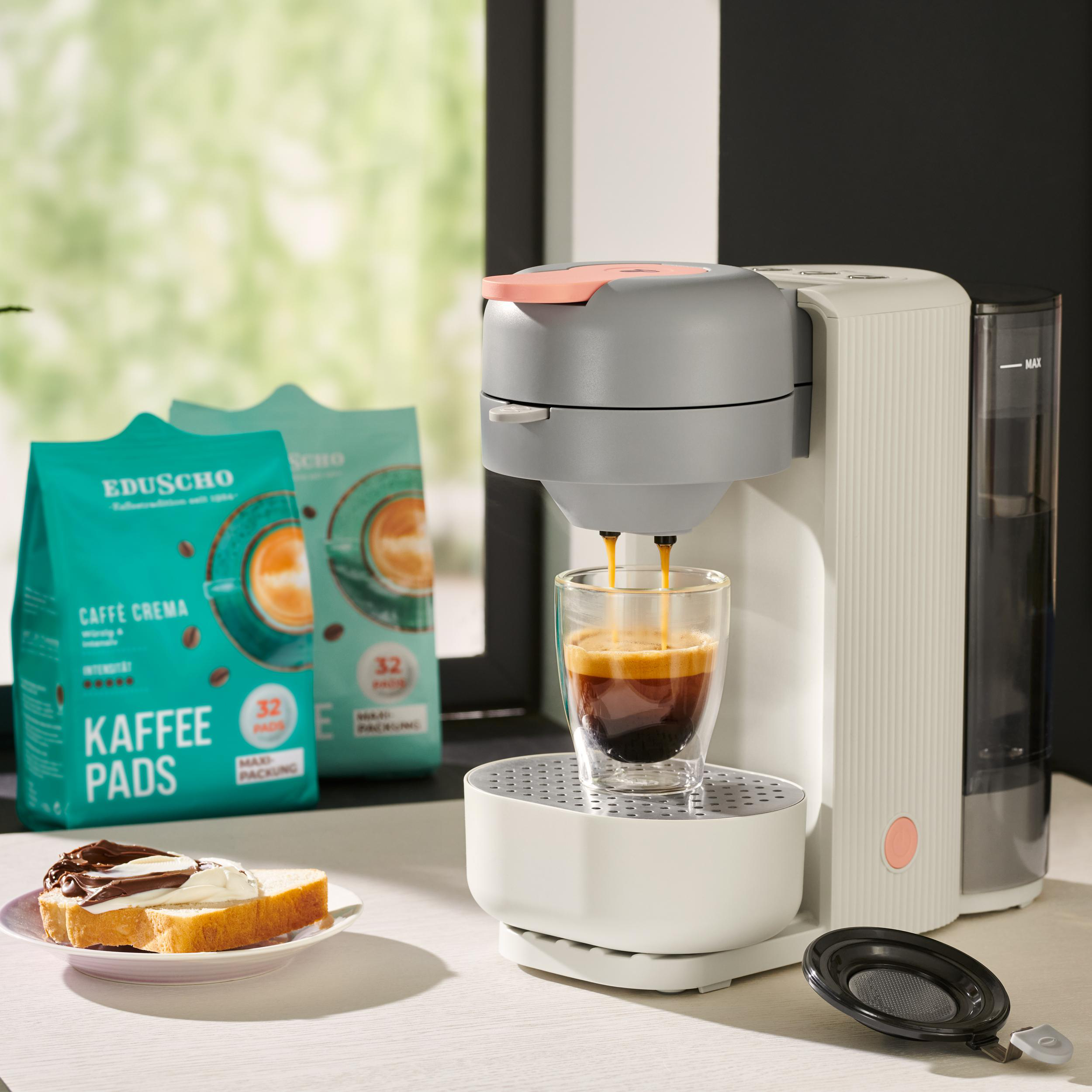 Espressomaschine, die Kaffee in ein Glas ausgibt. Kaffeepackungen im Hintergrund.