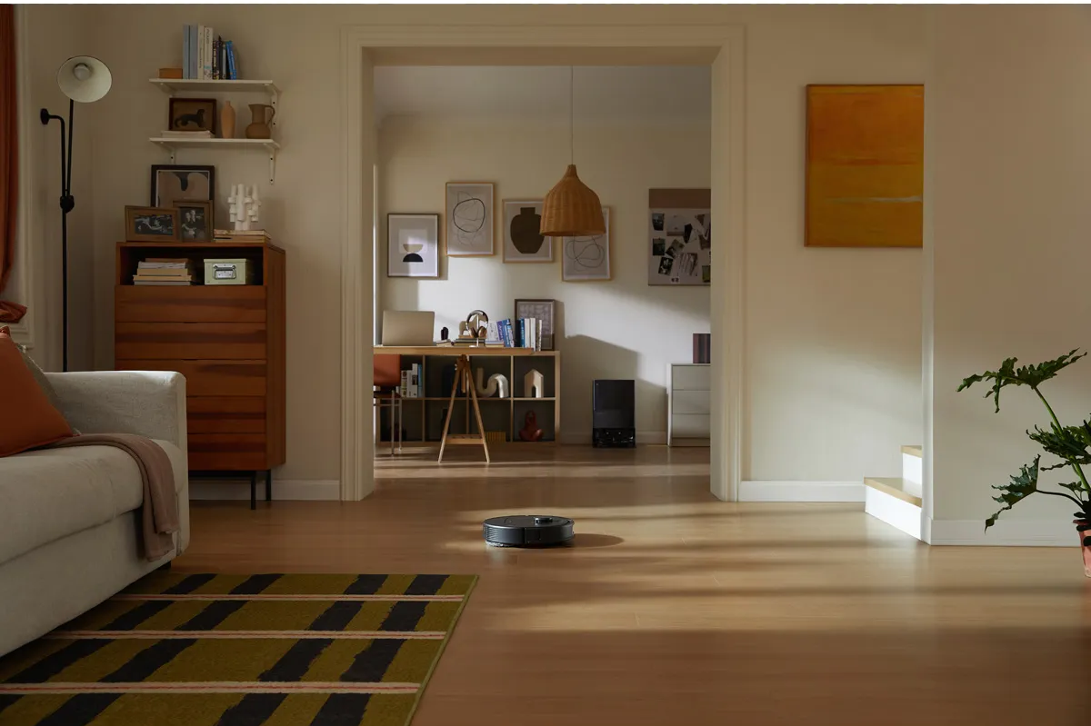 Roomba-Staubsauger reinigt Hartholzboden, Innenraum, Teppich im Vordergrund.