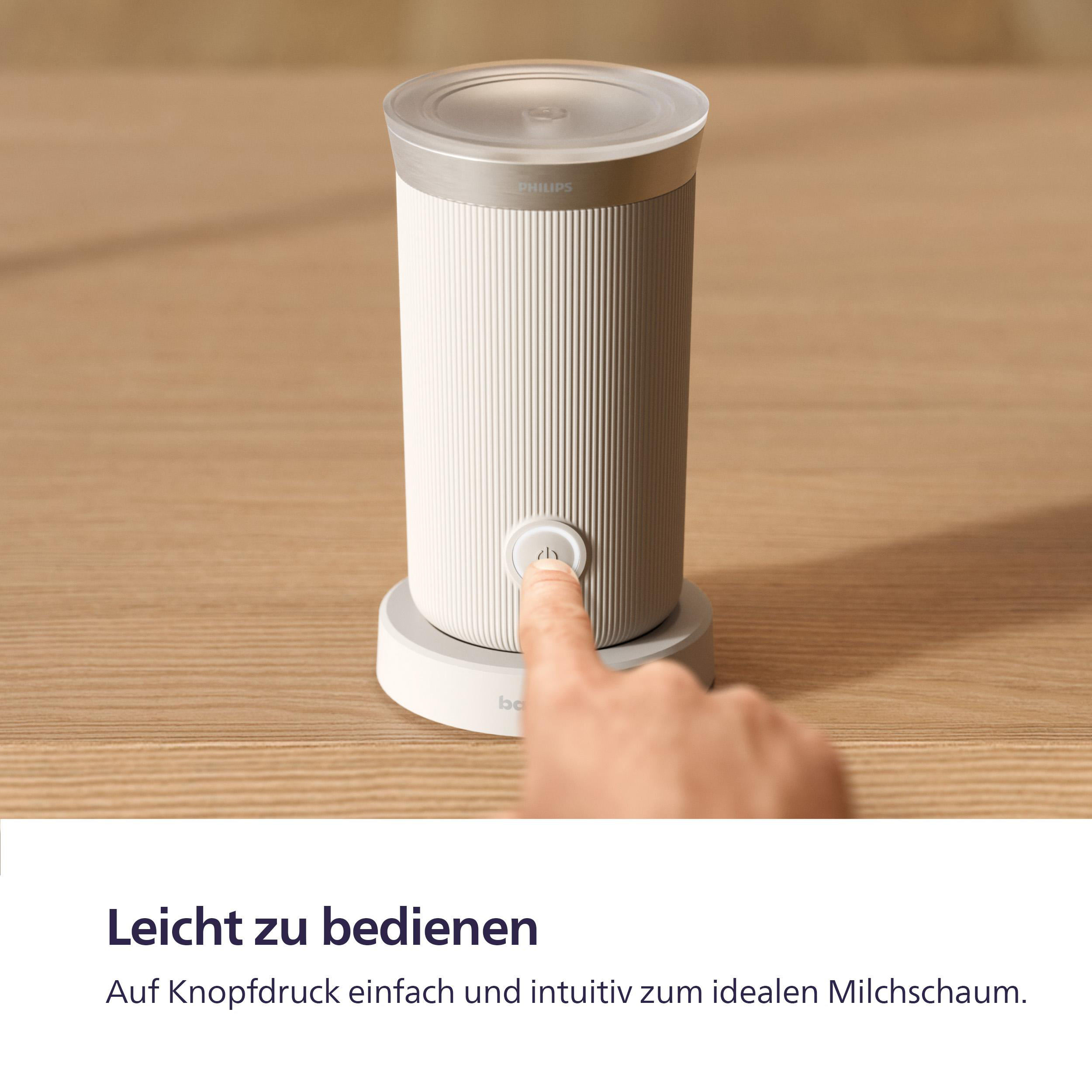 Weißer Milchaufschäumer mit silbernem Deckel und Knopf, der von einem Finger gedrückt wird.