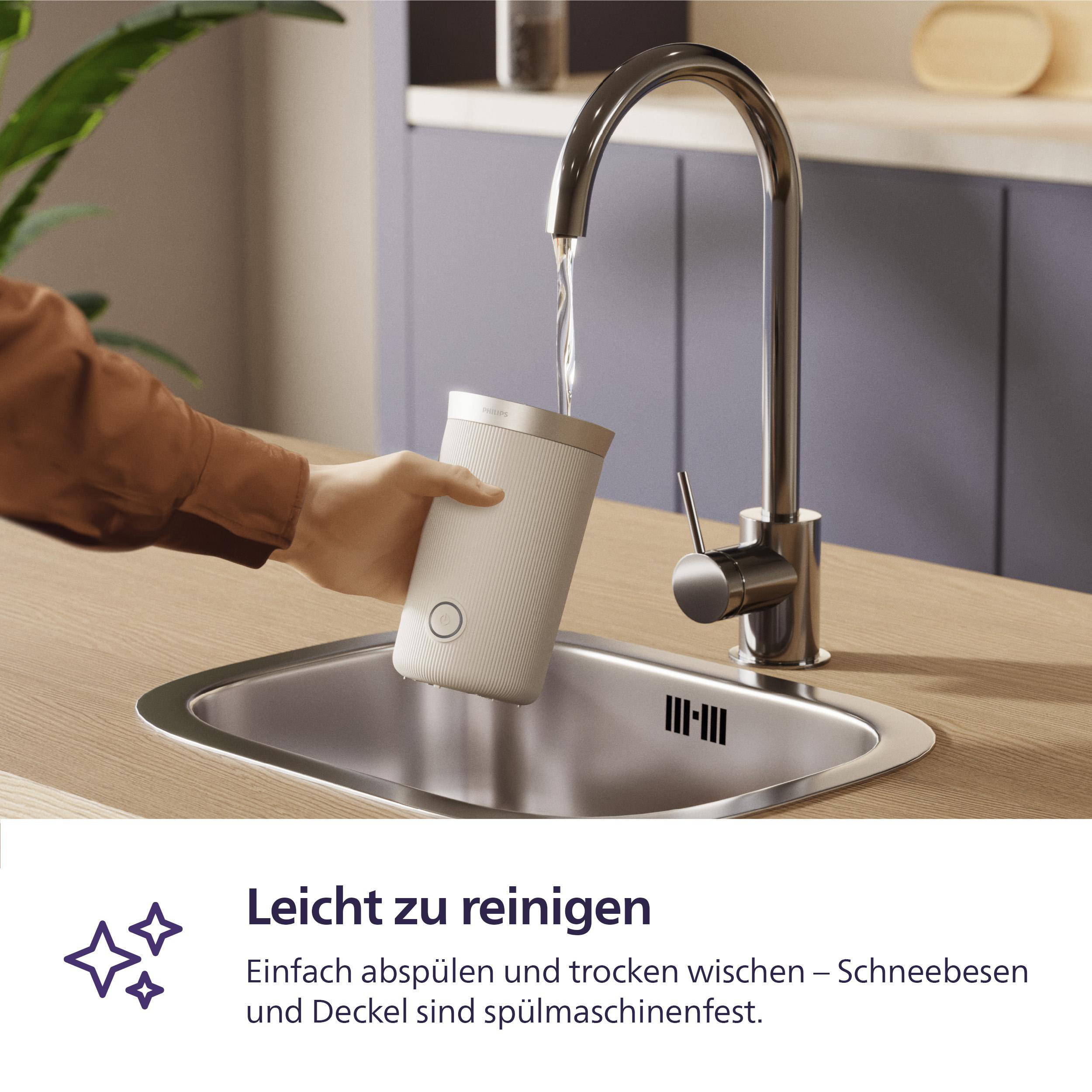 Eine Person wäscht ein weißes und goldenes Objekt unter einem Wasserhahn in einem Edelstahlbecken.