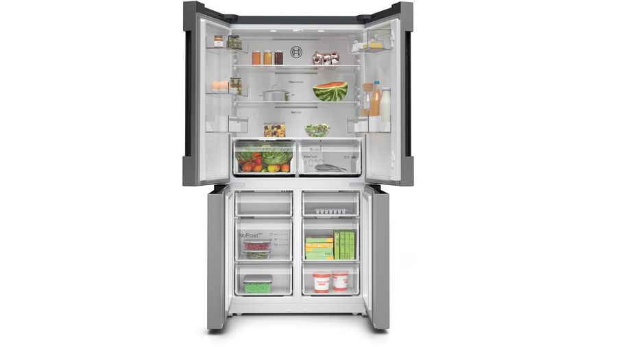 Refrigerador abierto de acero inoxidable. Tiene alimentos y bebidas en estantes y cajones.