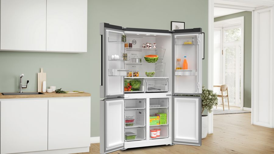 Refrigerador abierto con estantes llenos de alimentos: verduras, bebidas, frutas.