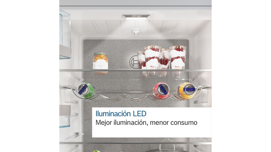 Interior de refrigerador con tarro, postres y latas. La luz LED está encendida.