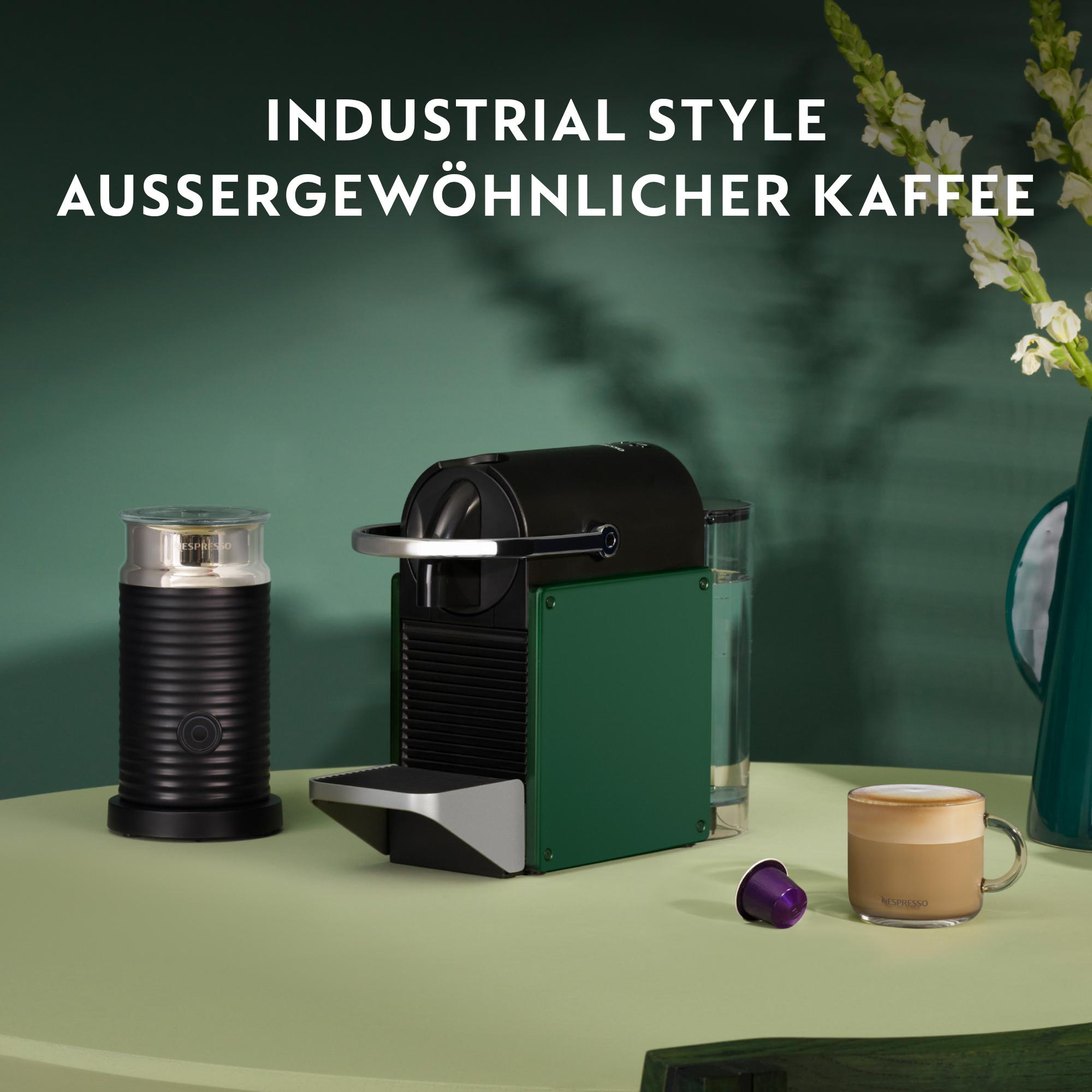 Kaffeemaschine mit Milchaufschäumer, Kaffeetasse und Kaffeekapsel auf einem Tisch.