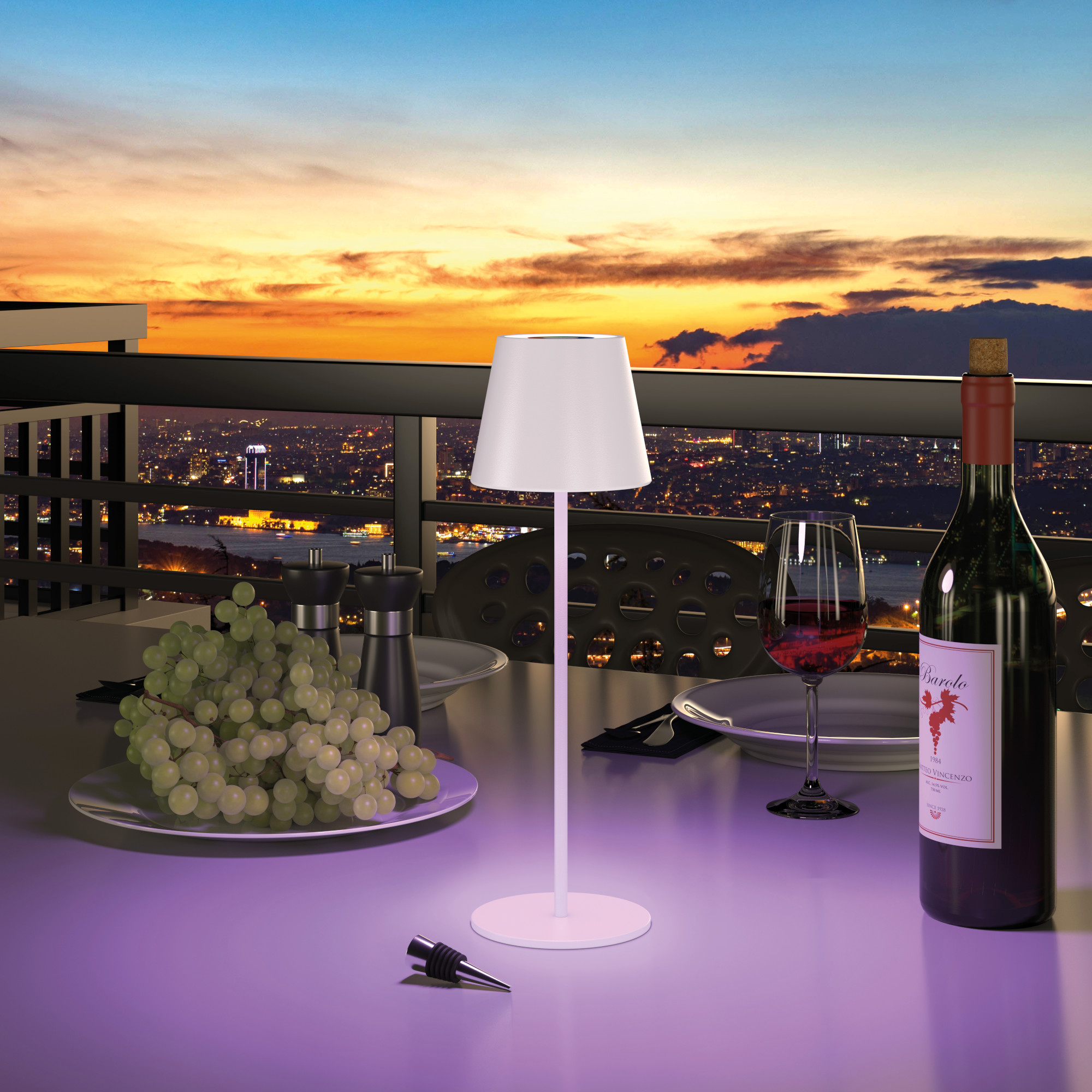 Tisch mit Lampe, Wein, Trauben und Stadtlandschaft bei Sonnenuntergang.
