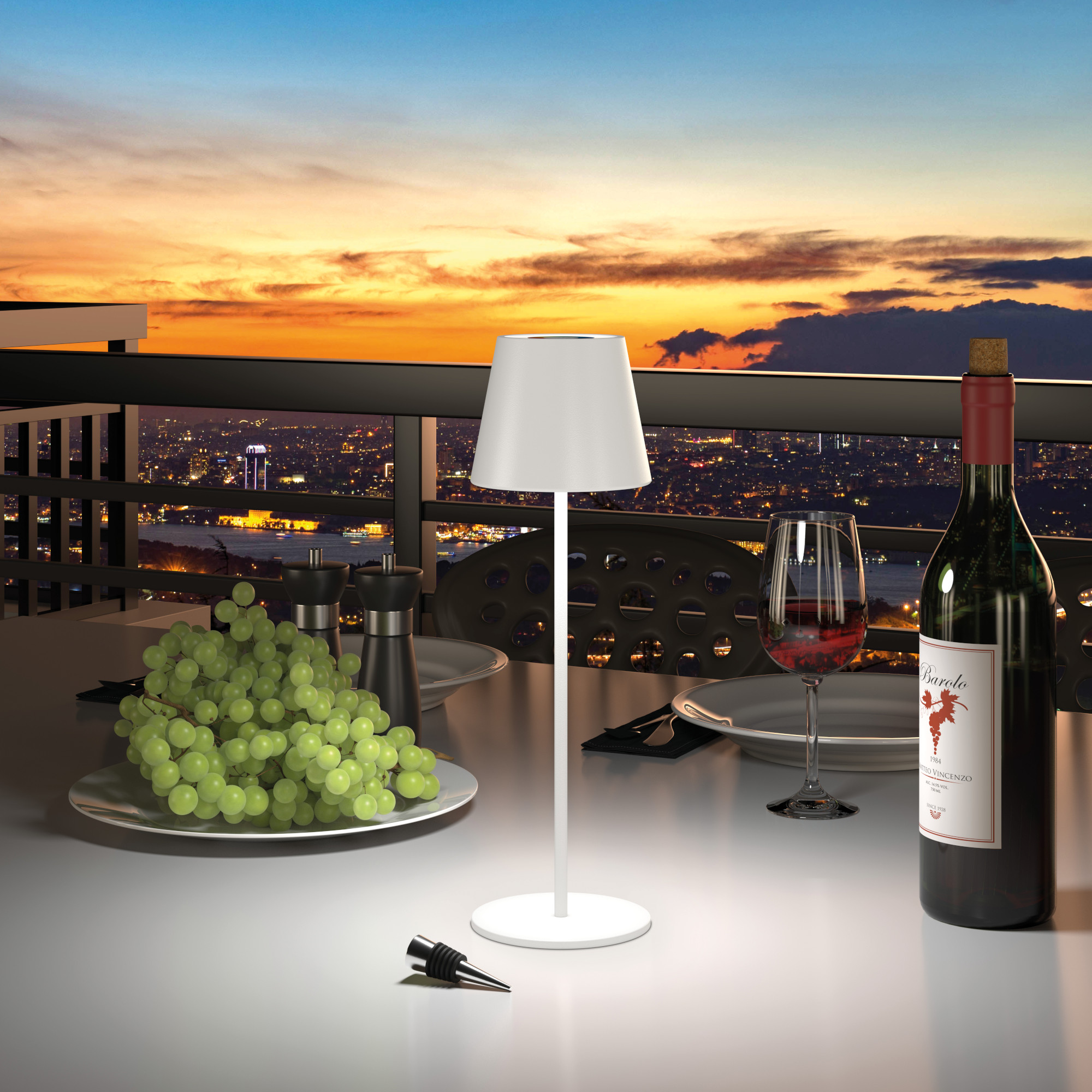 Szene im Freien: ein Tisch mit Wein, einer Lampe, Trauben und einer Skyline bei Sonnenuntergang.