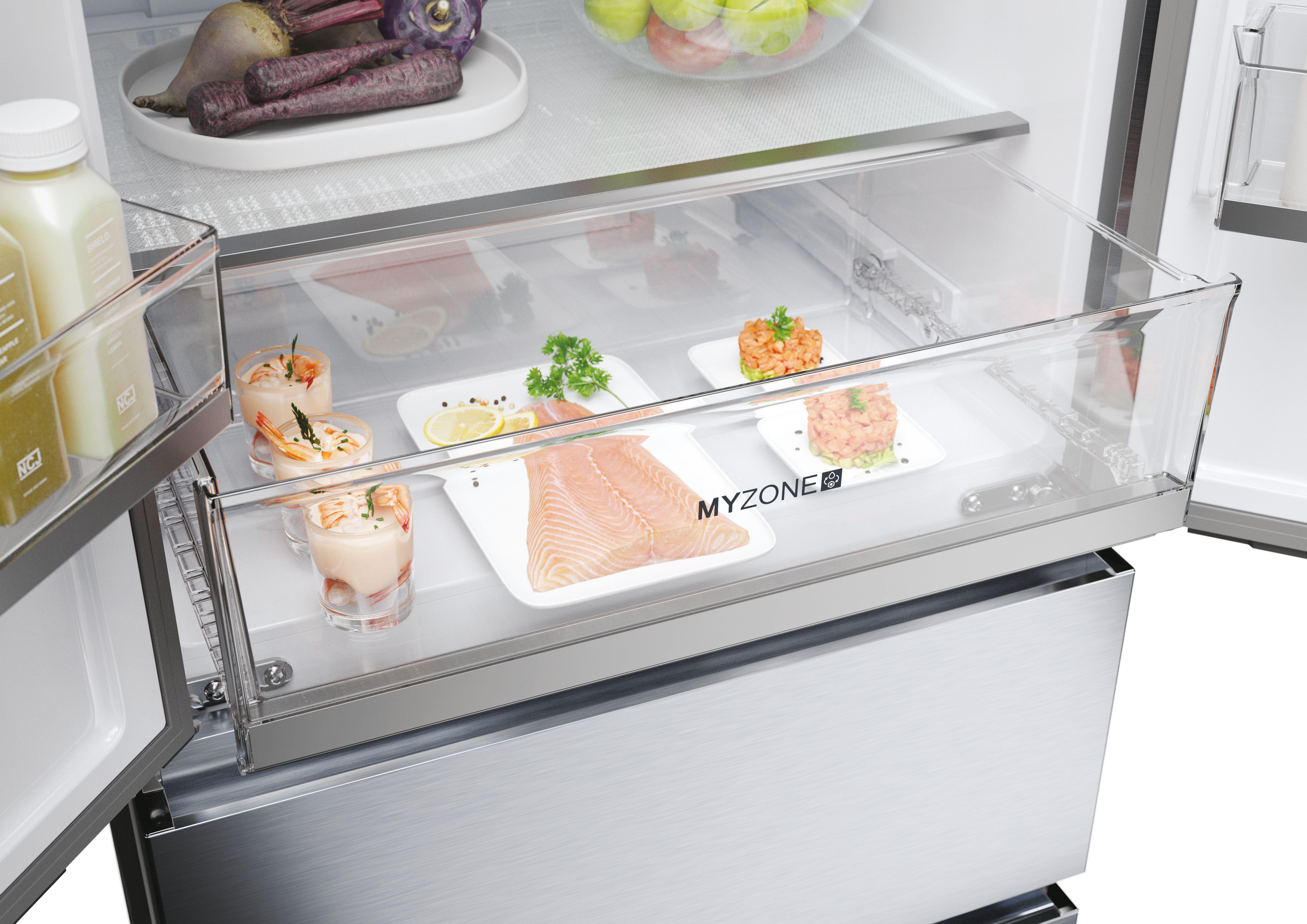 Offener Kühlschrank mit einer durchsichtigen Schublade, die Lebensmittel wie Garnelen, Lachs und Gemüse enthält.