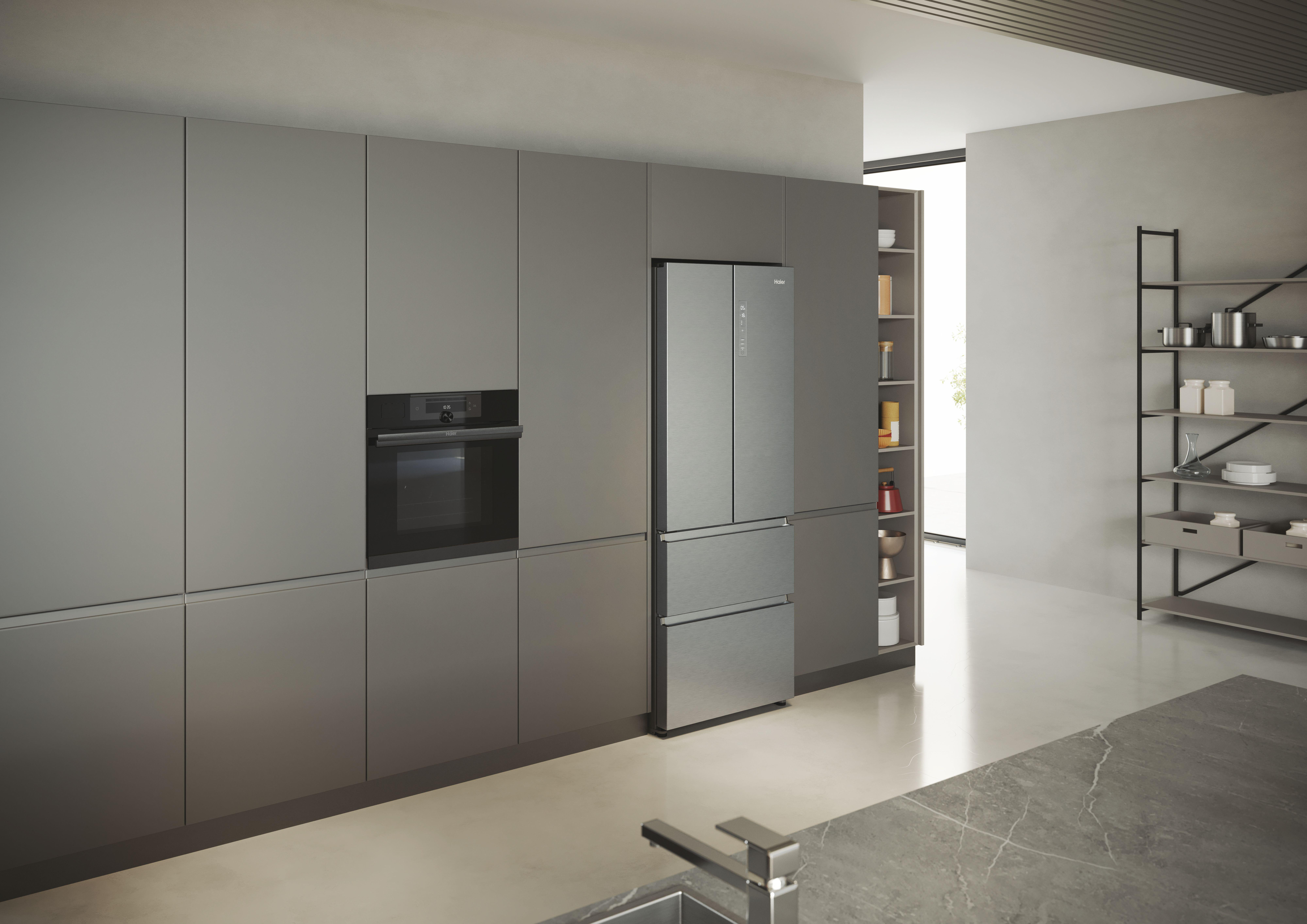 Eine Küche mit grauen Schränken, einem Kühlschrank und einem Backofen. Ein Edelstahlbecken ist sichtbar.