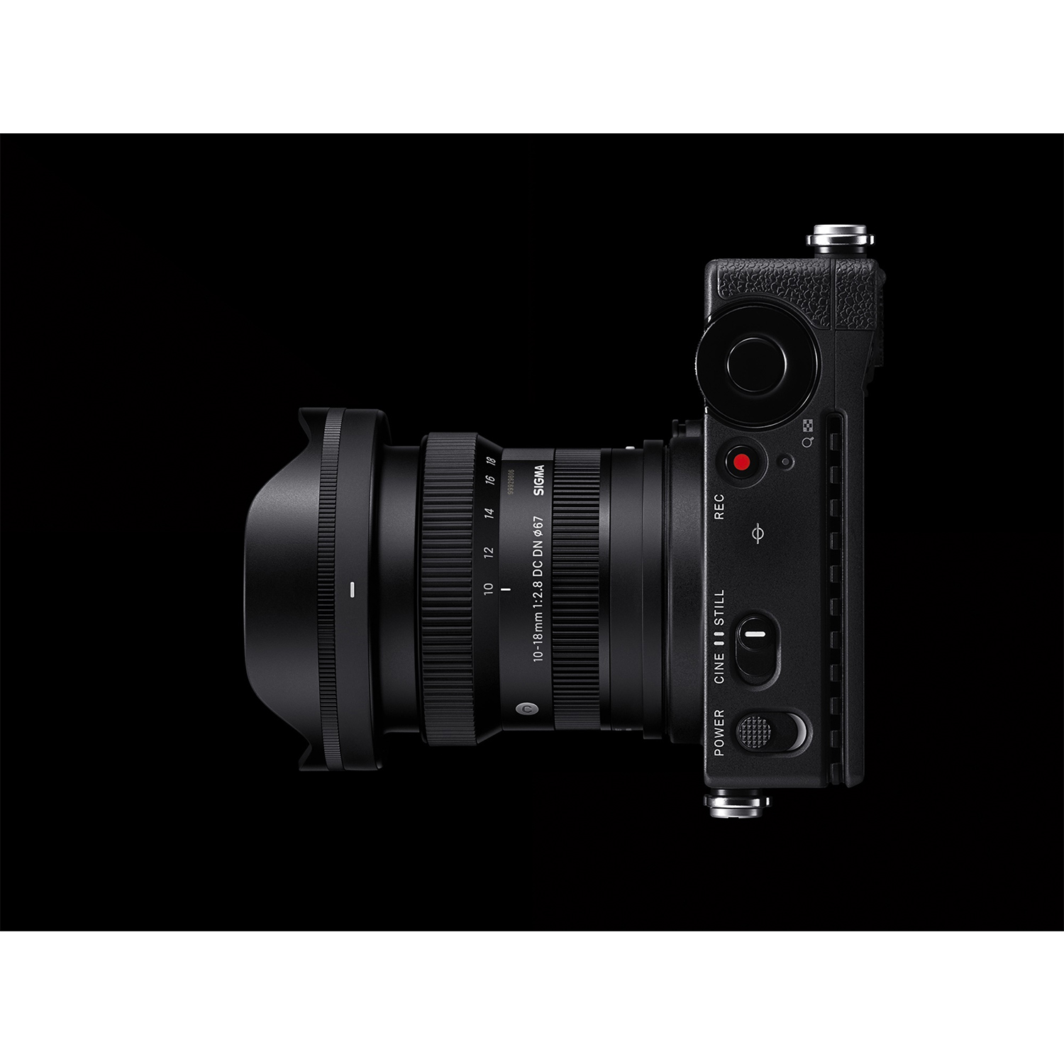 Fotocamera con obiettivo. Corpo nero, obiettivo focalizzato, su sfondo nero.