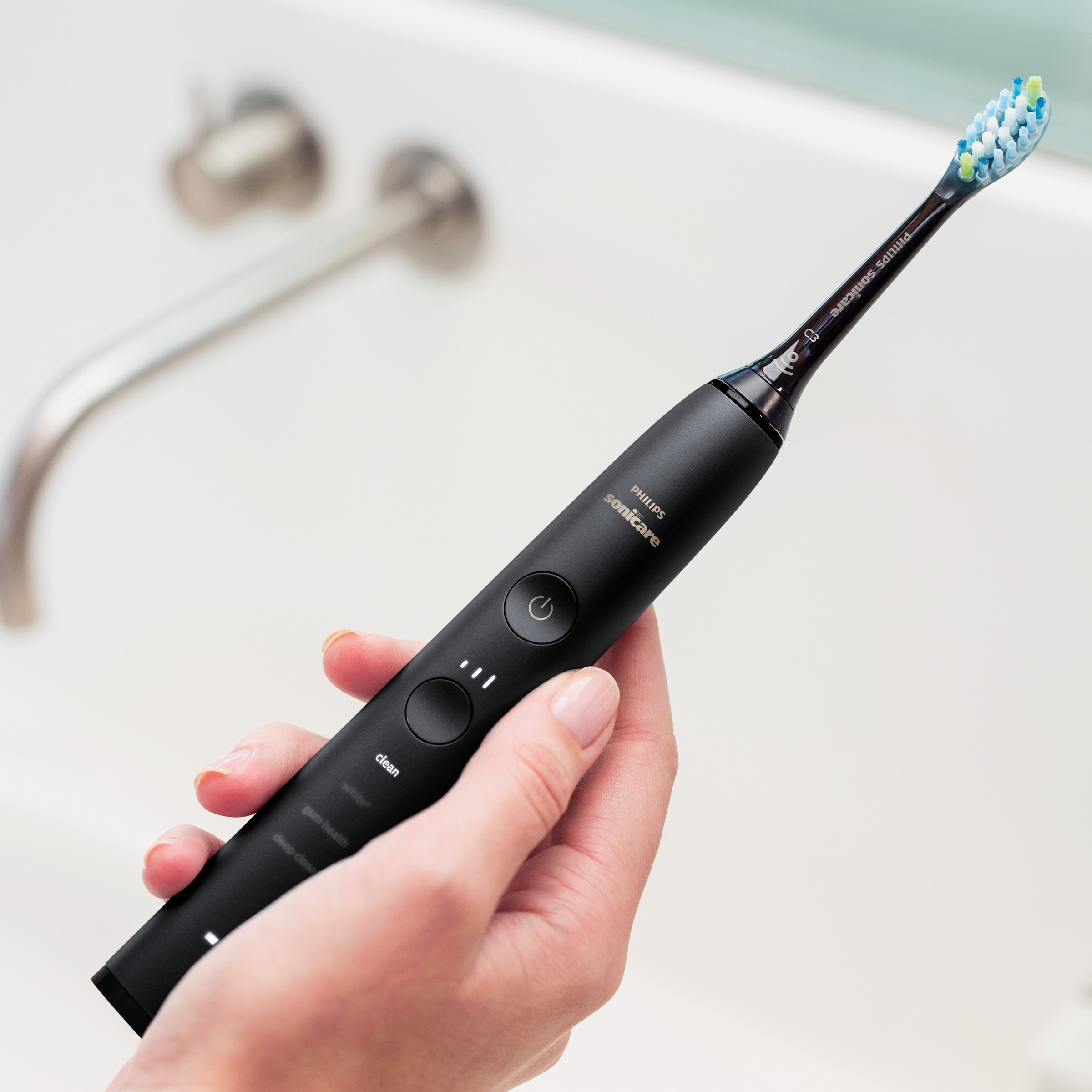 Czarna elektryczna szczoteczka do zębów Philips Sonicare trzymana nad zlewem.