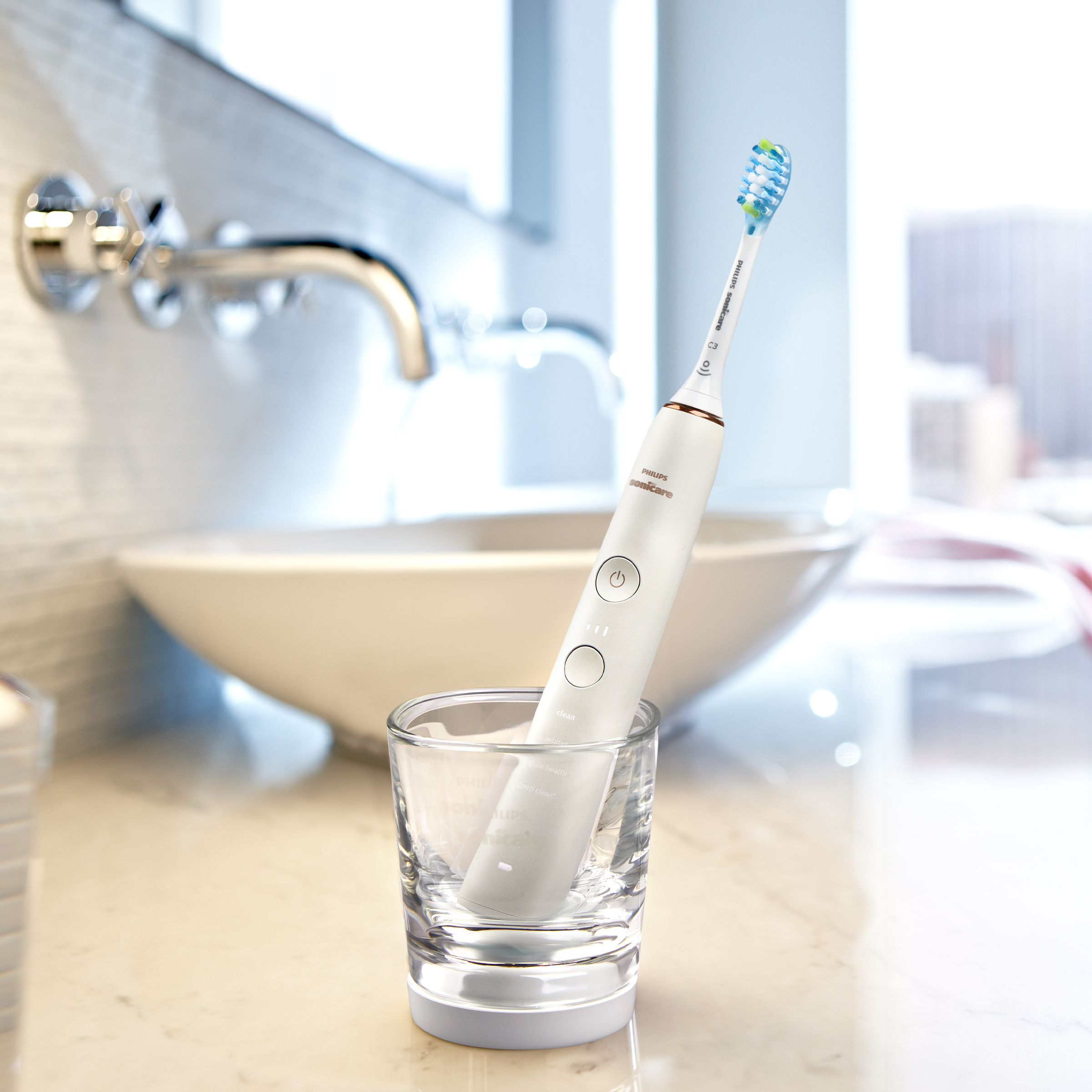 Biała szczoteczka elektryczna w szklance, w łazience.