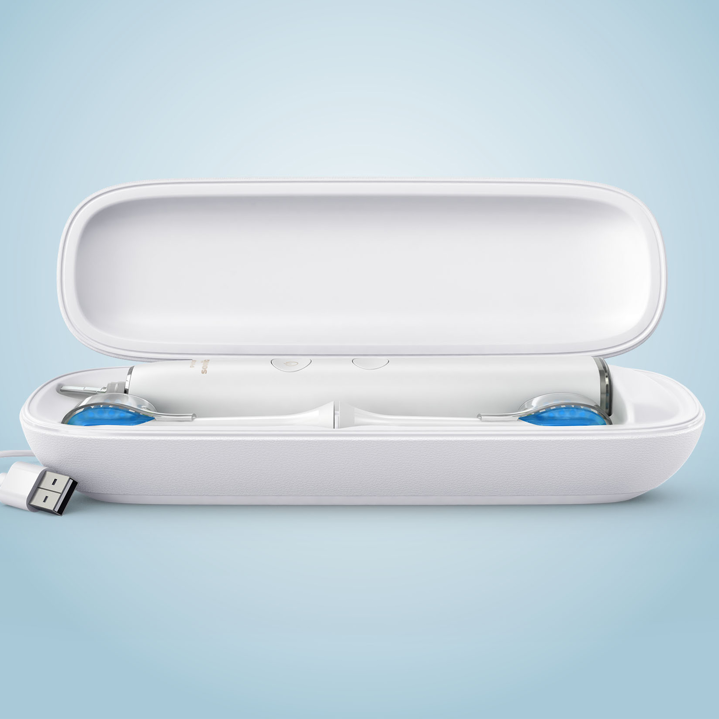 Otwarta biała obudowa podróżna ze szczoteczką elektryczną i dwiema końcówkami. Dołączony kabel USB.