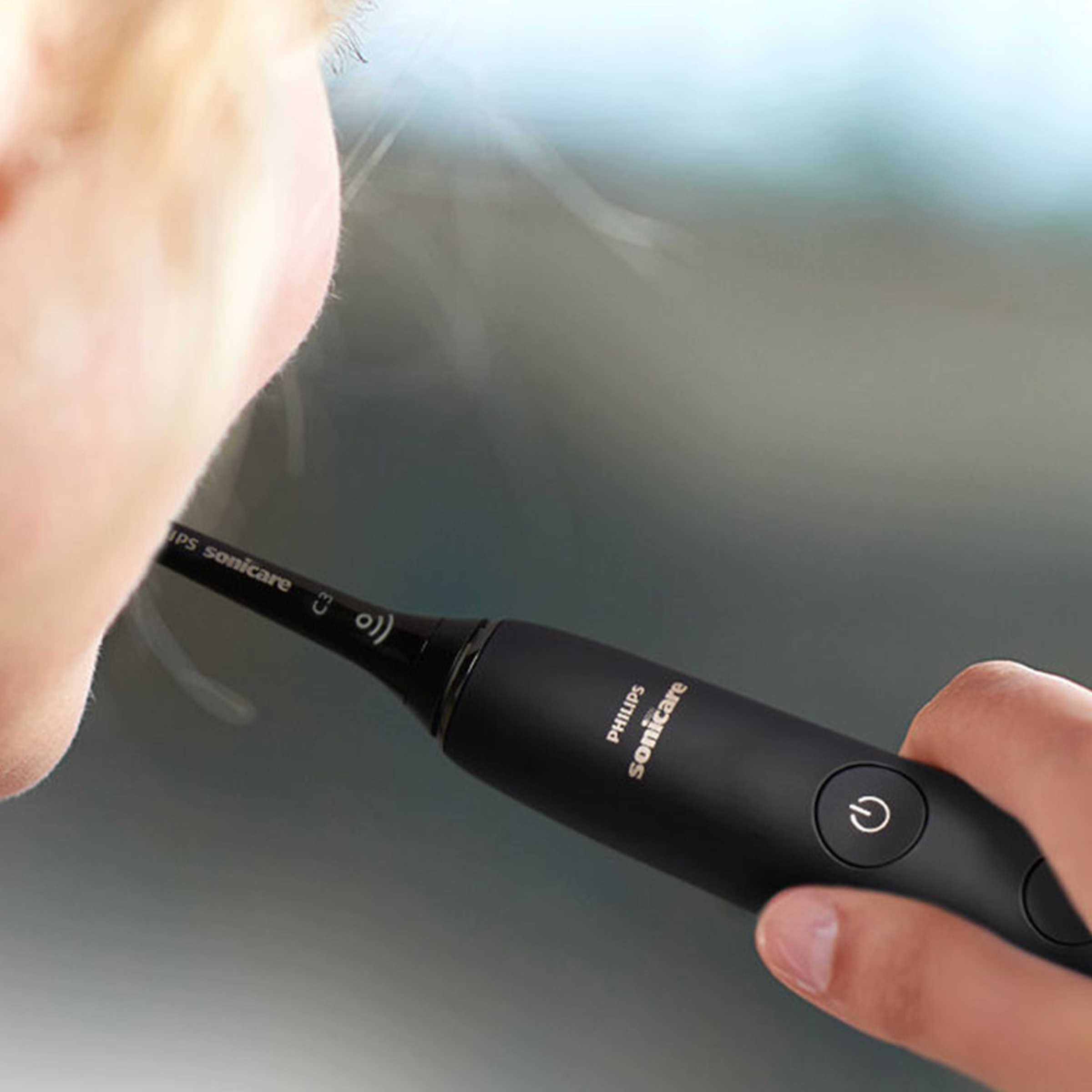 Osoba używająca czarnej szczoteczki Philips Sonicare w ustach.