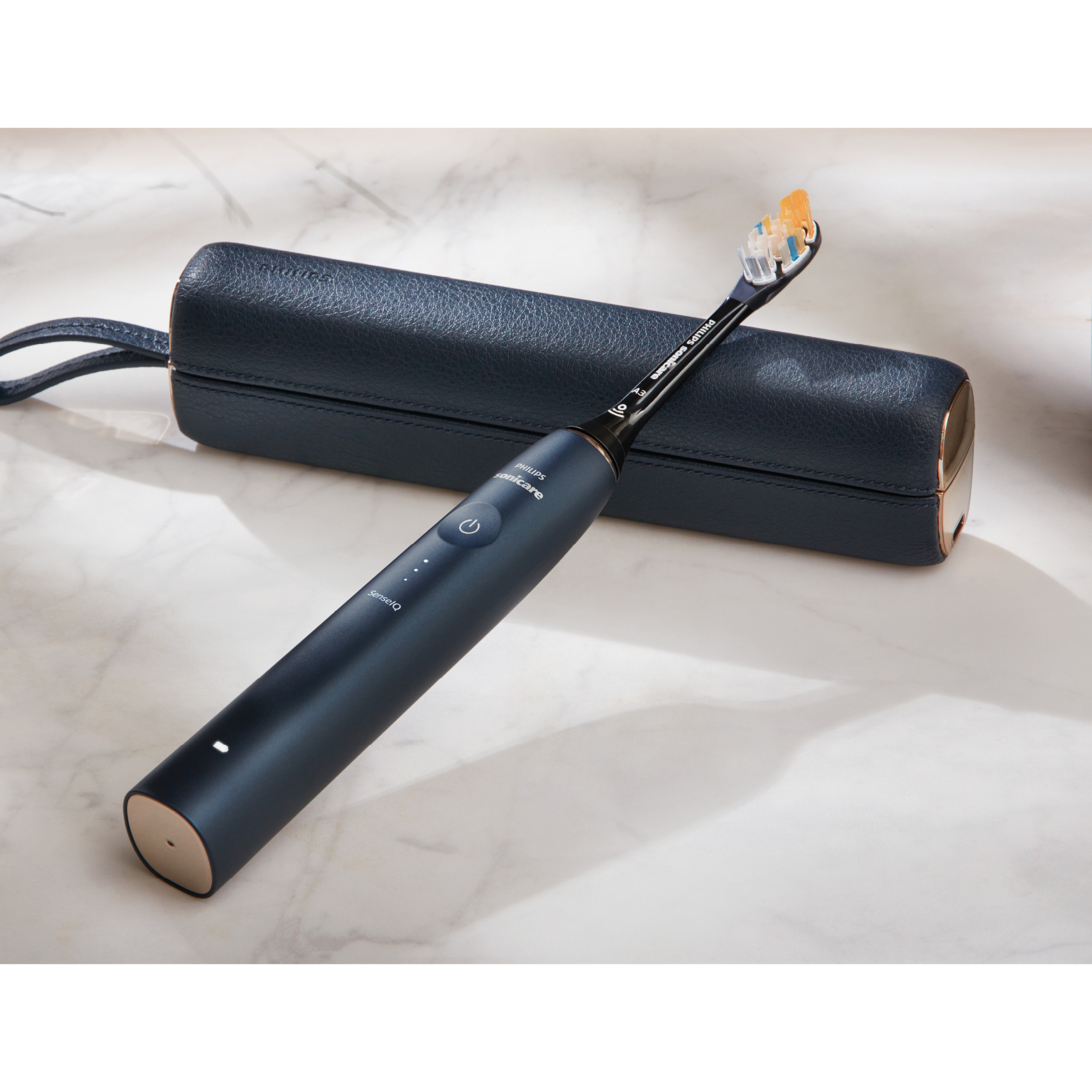 Czarna i złota elektryczna szczoteczka do zębów, leżąca obok etui.