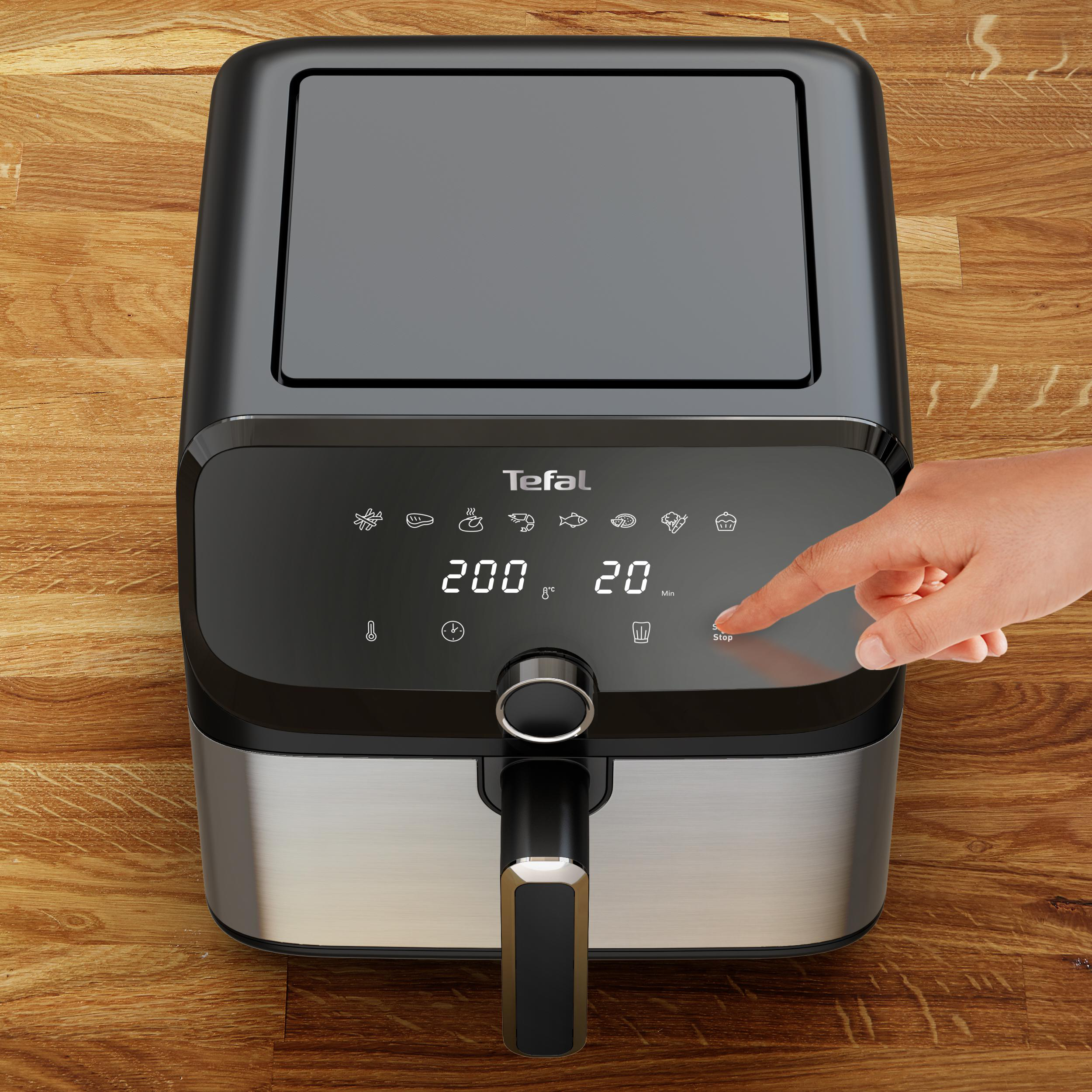 Eine Heißluftfritteuse, bei der eine Hand eine Taste auf dem Digitaldisplay drückt.