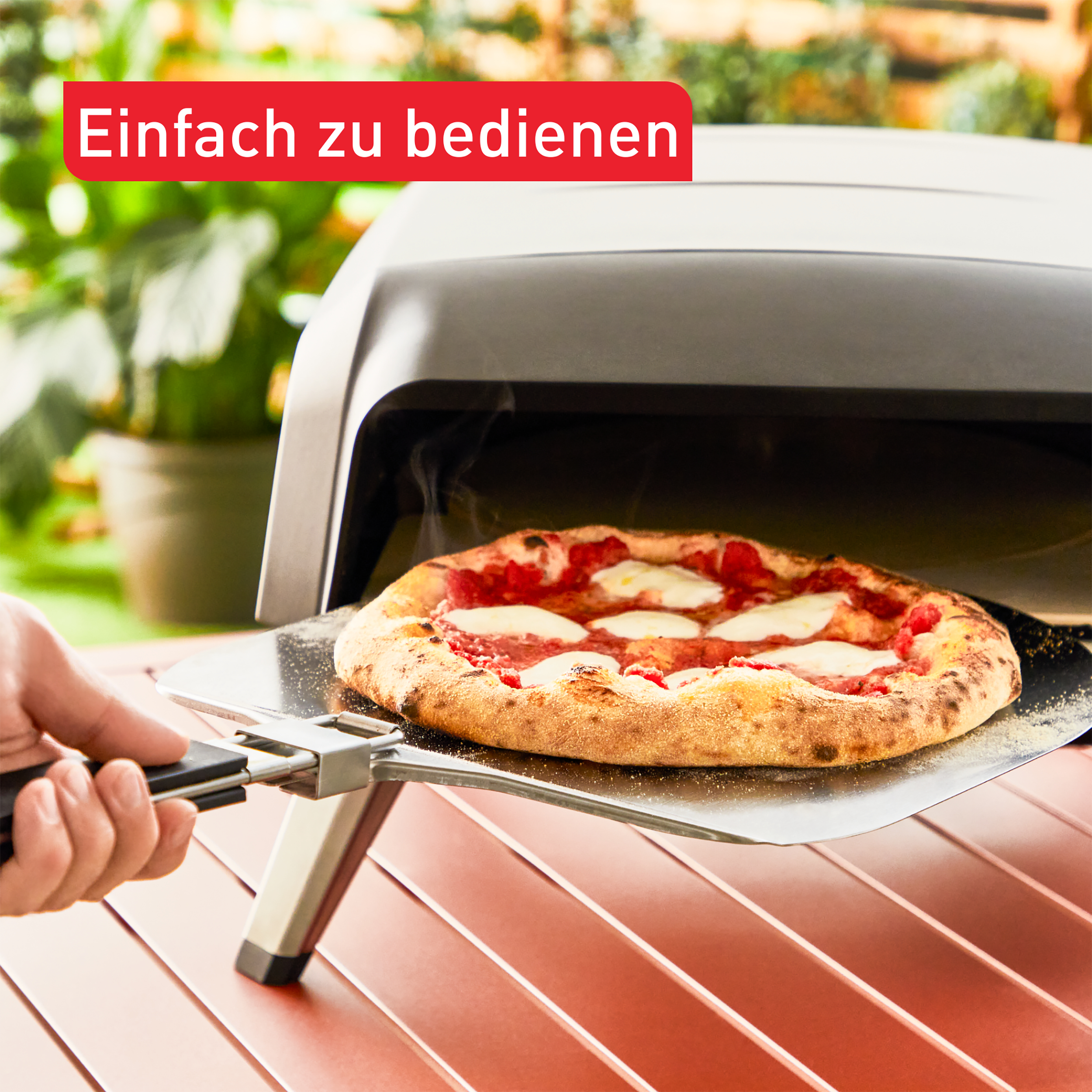 Pizza wird mit einer Pizzaschaufel aus einem Außenofen genommen.