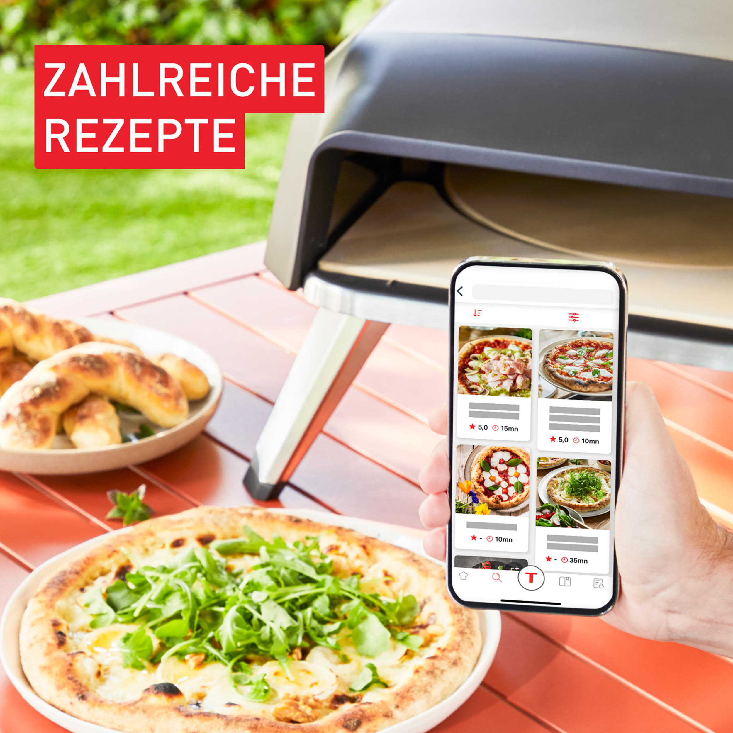 Eine Person, die ein Smartphone mit Pizzarezepte verwendet. Pizza und Ofen stehen auf dem Tisch.