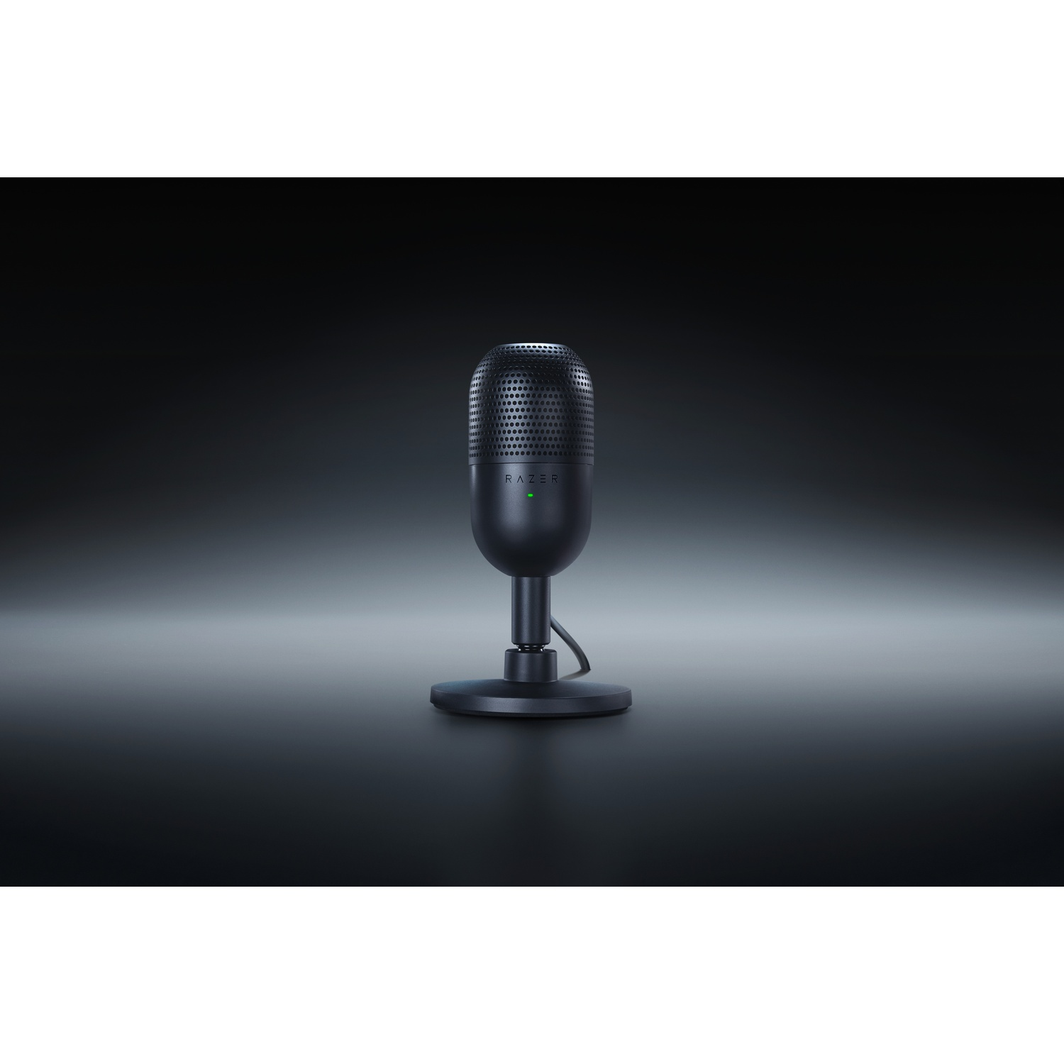 Un microphone noir sur un support sur une surface sombre, avec une lumière verte allumée.