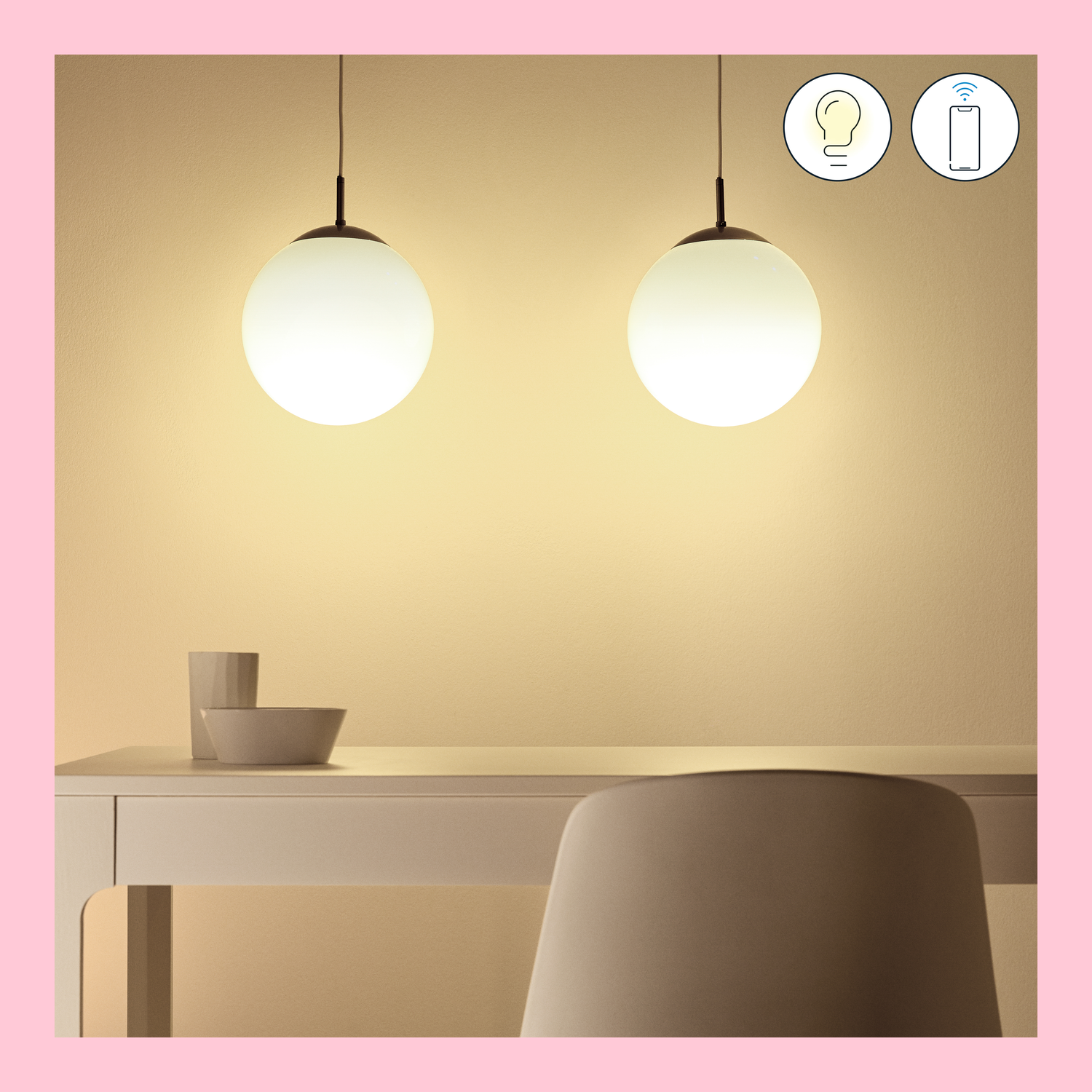 Two hanging round lights. A table and chair are beneath them. The background is a plain wall.