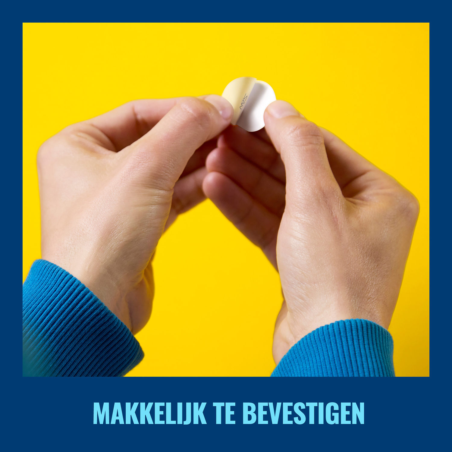 Handen die een kleine zilveren sticker vasthouden tegen een gele achtergrond. Blauwe mouwen.