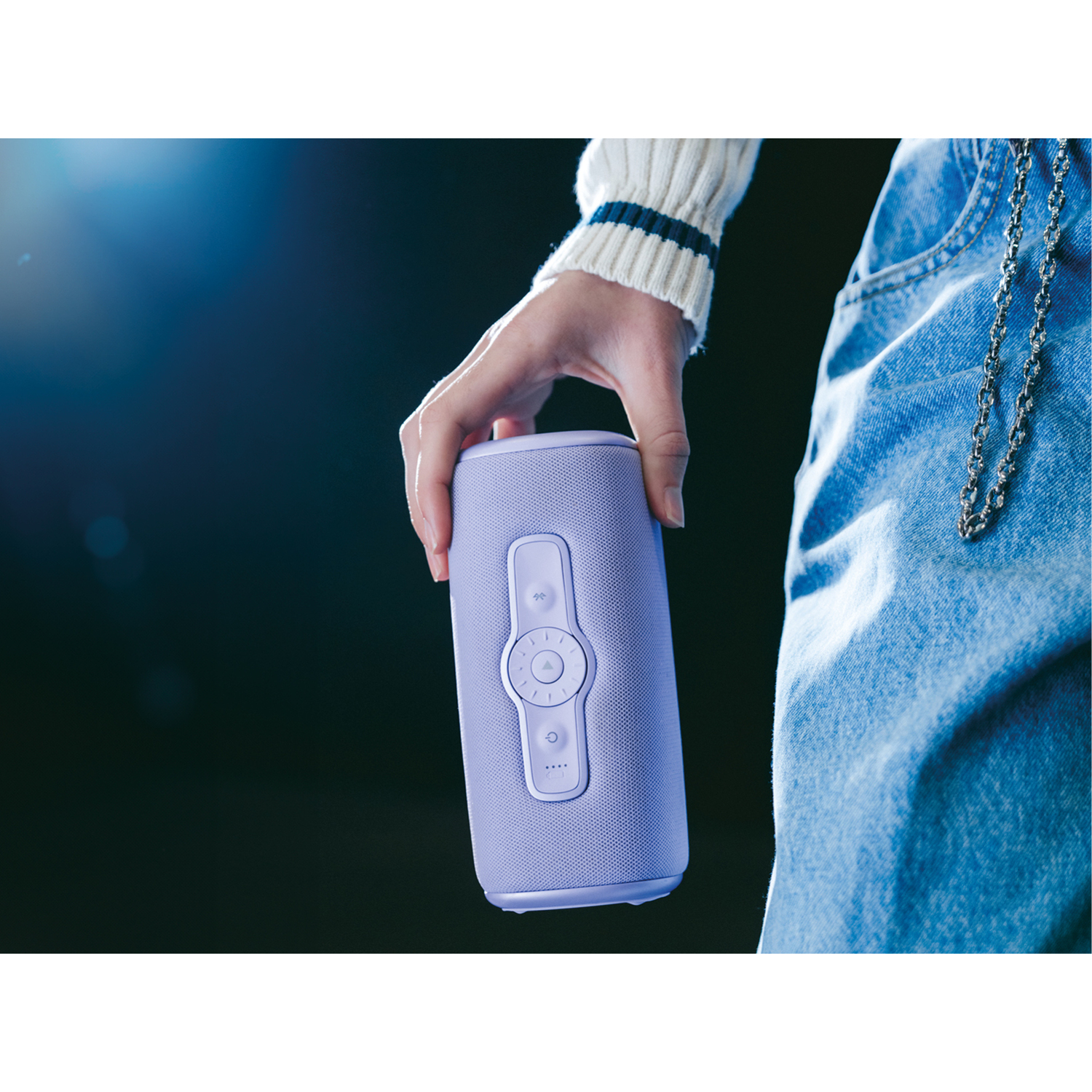A person holding a purple speaker with controls.