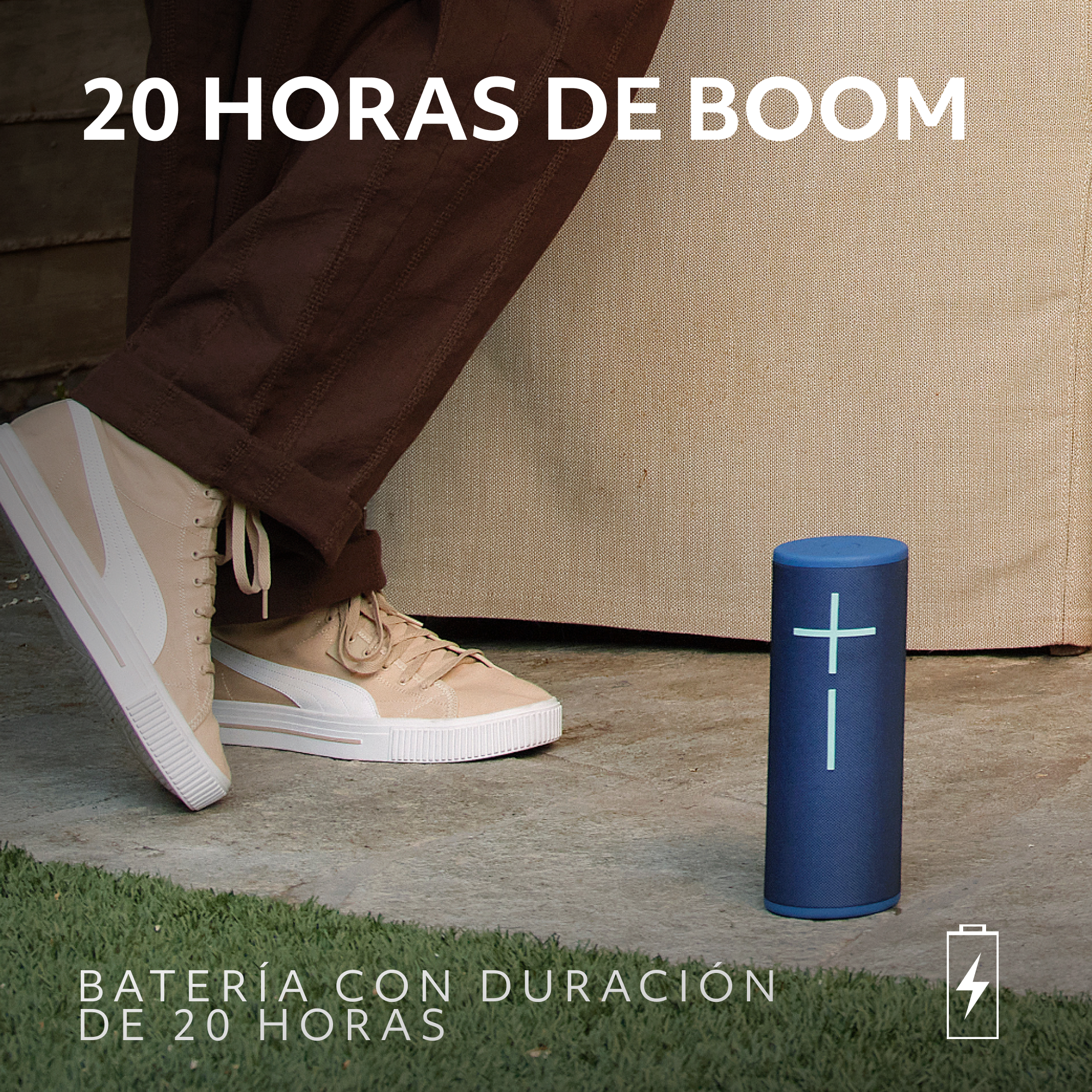 Un altavoz azul en el suelo cerca de una persona con zapatillas. Texto en español: 20 horas de boom. Batería 20 horas.