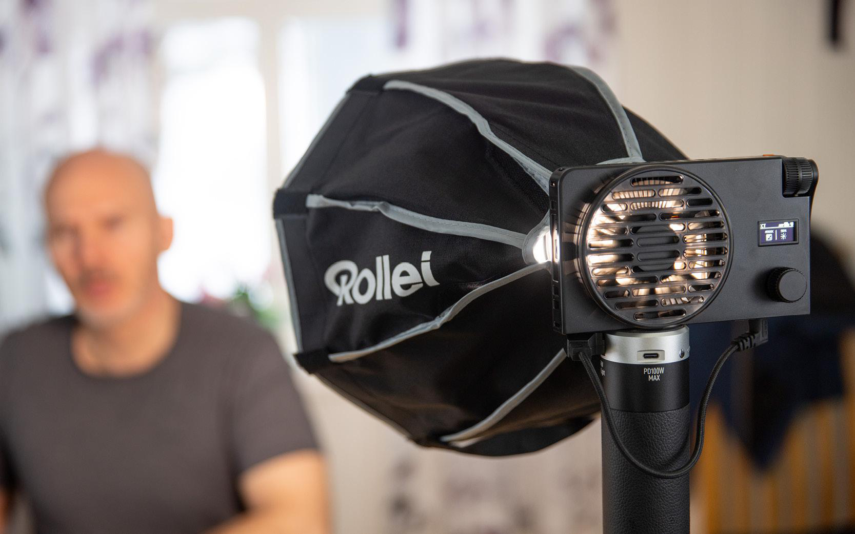 Ein Mann hinter einem Lichtaufbau mit Softbox. Das Licht ist auf den Mann gerichtet.