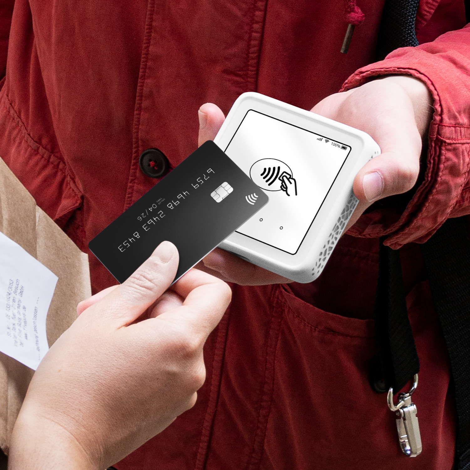 Une personne tend une carte noire à une autre personne qui tient un appareil de paiement blanc.