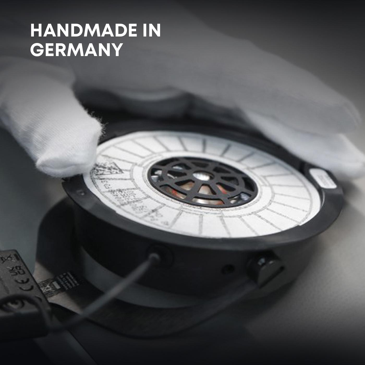 Nahaufnahme eines Kopfhörer-Treibers, gehalten von einer behandschuhten Hand. Text 'Handmade in Germany'.