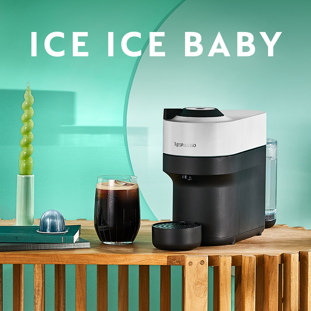 Une machine à café et un verre de café, avec une bougie et un glaçon dans le cadre.