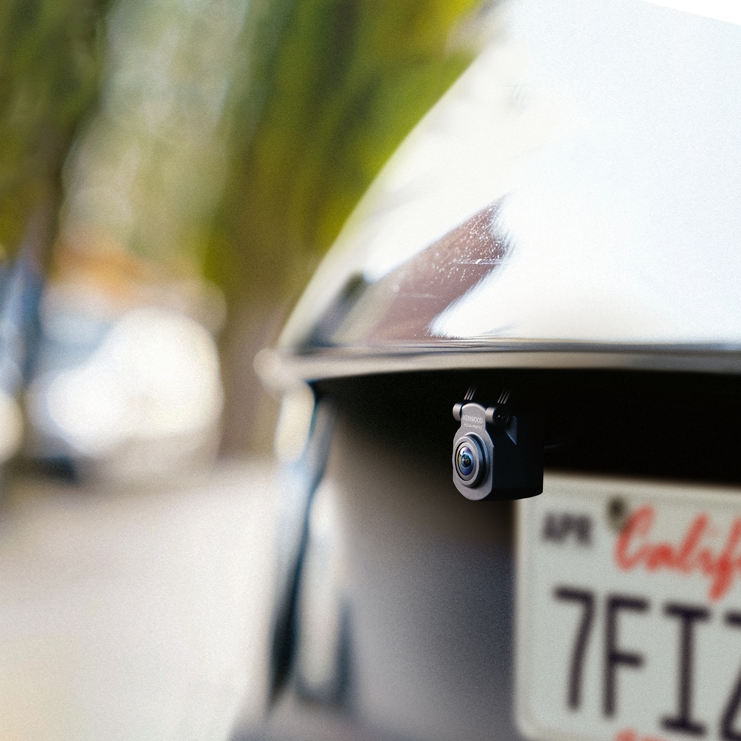 A dashcam mounted on a car’s rear. It is black and mounted above the license plate.