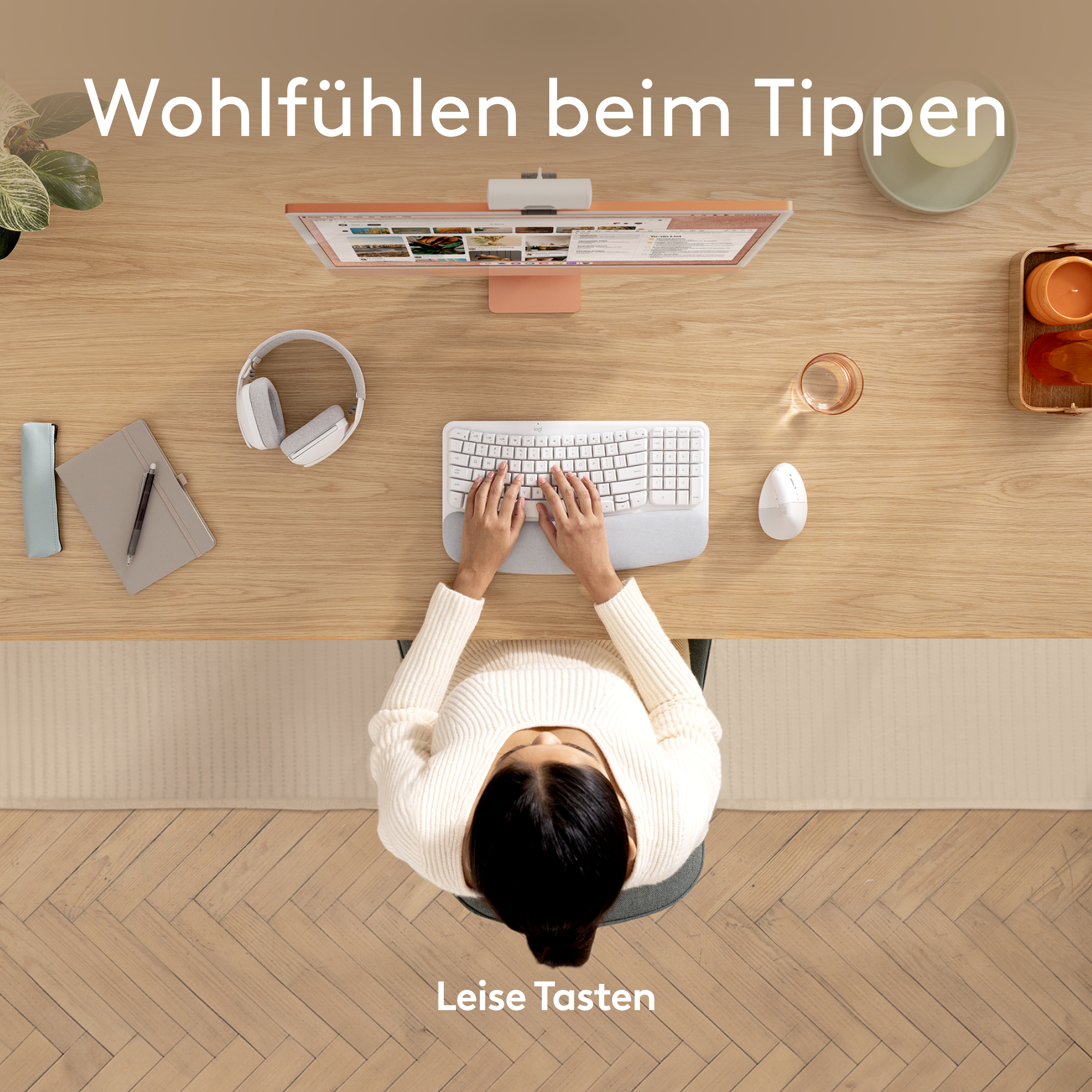 Person schreibt an einem Holztisch, mit Monitor, Maus und Kopfhörern.
