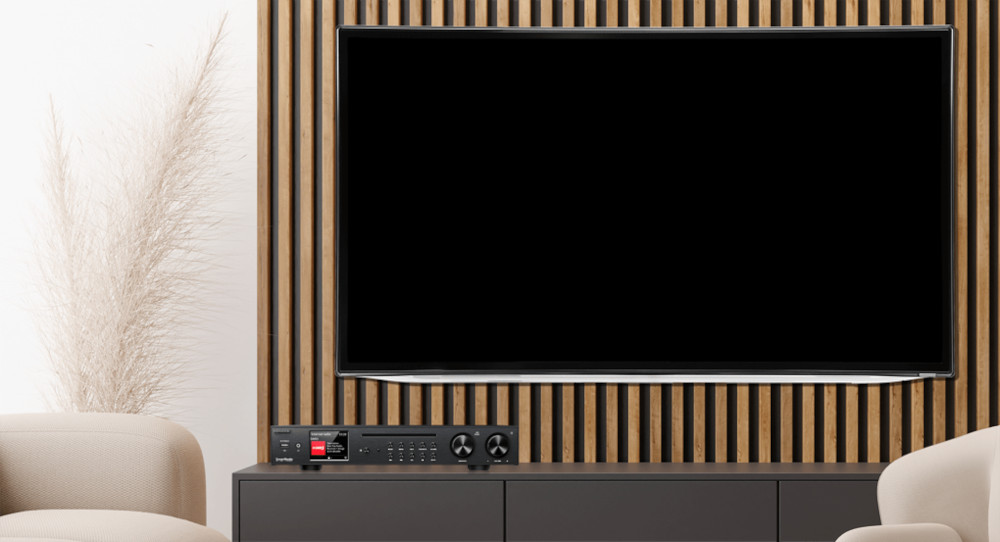 Large, black screen TV. Black cabinet with a sound system. Beige chairs and wooden wall.