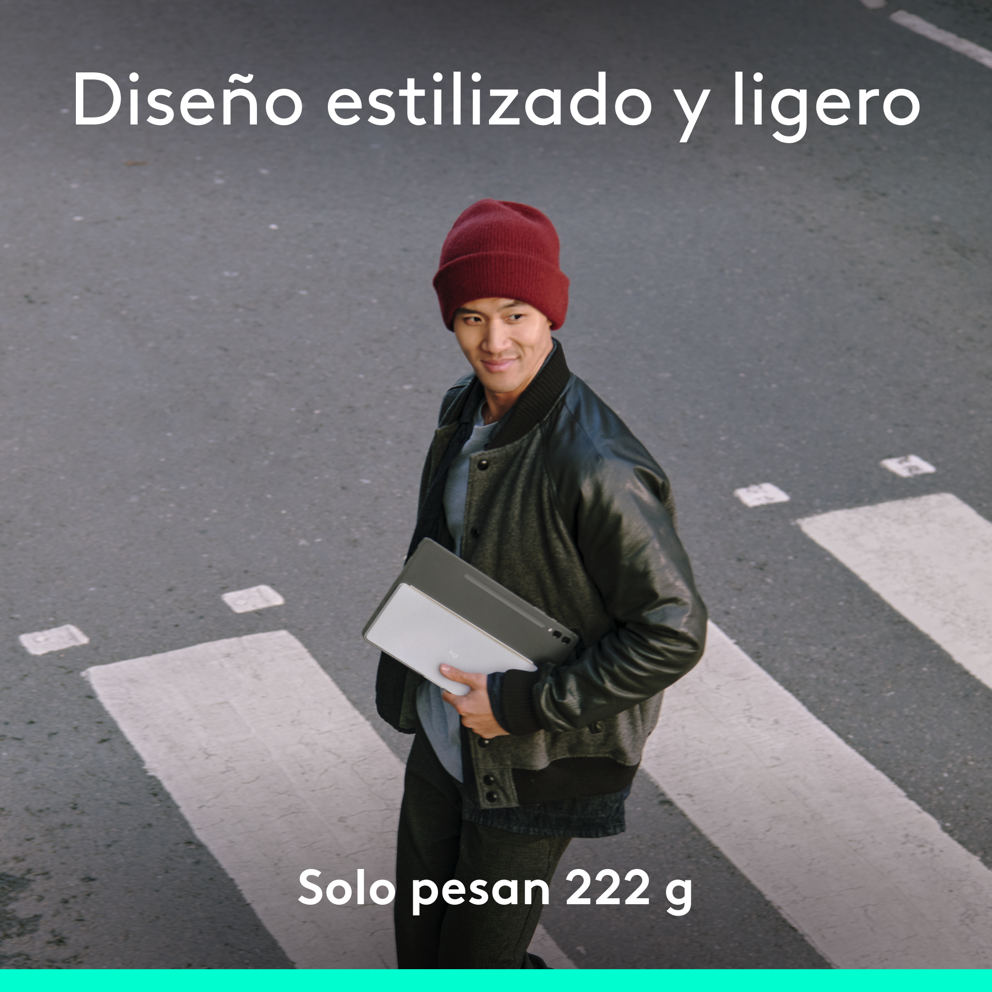 Hombre con gorro rojo y chaqueta, sosteniendo una tableta, caminando por un paso de cebra.