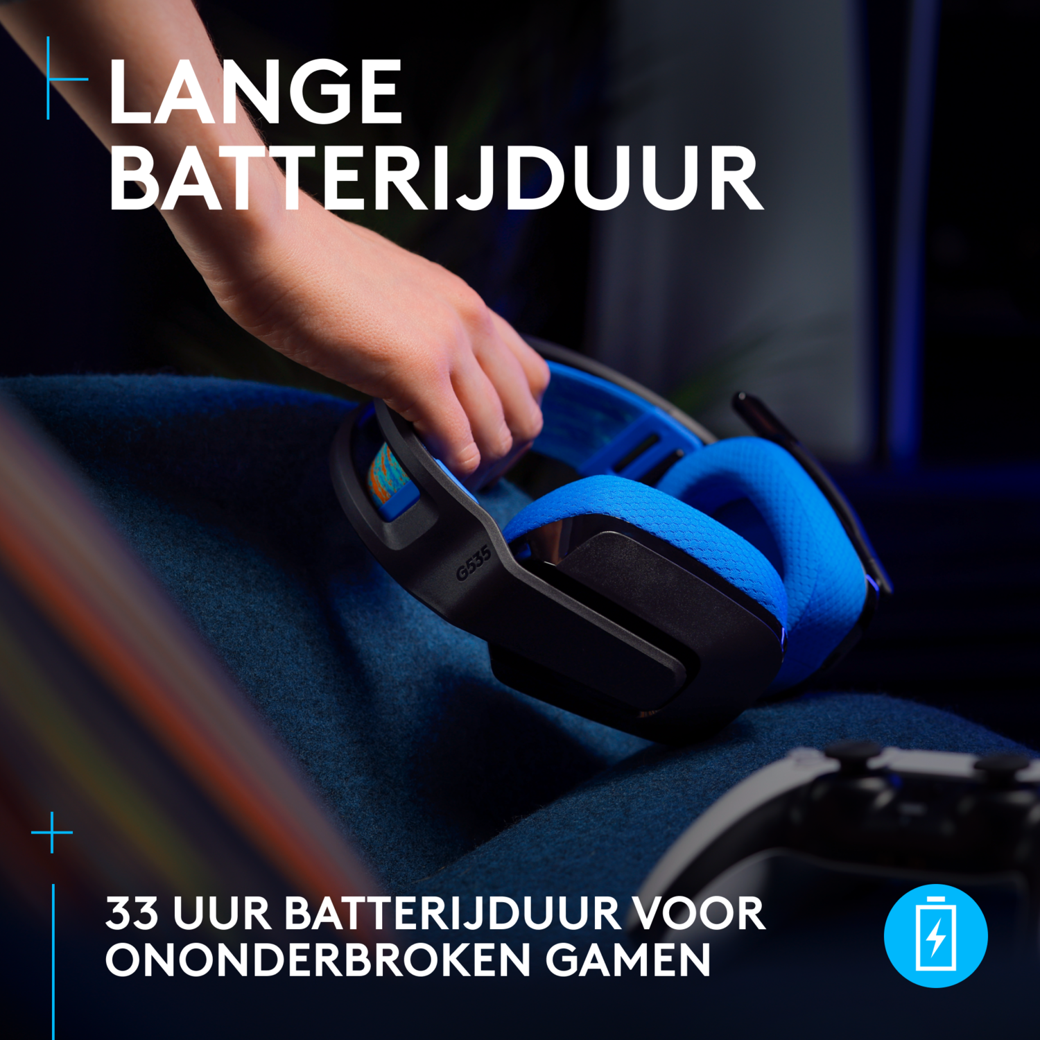 Person's hand reaching for blue and black gaming headset on a blue blanket.