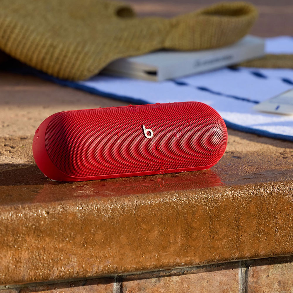 Haut-parleur rouge, cylindrique avec logo blanc sur surface mouillée, serviette.