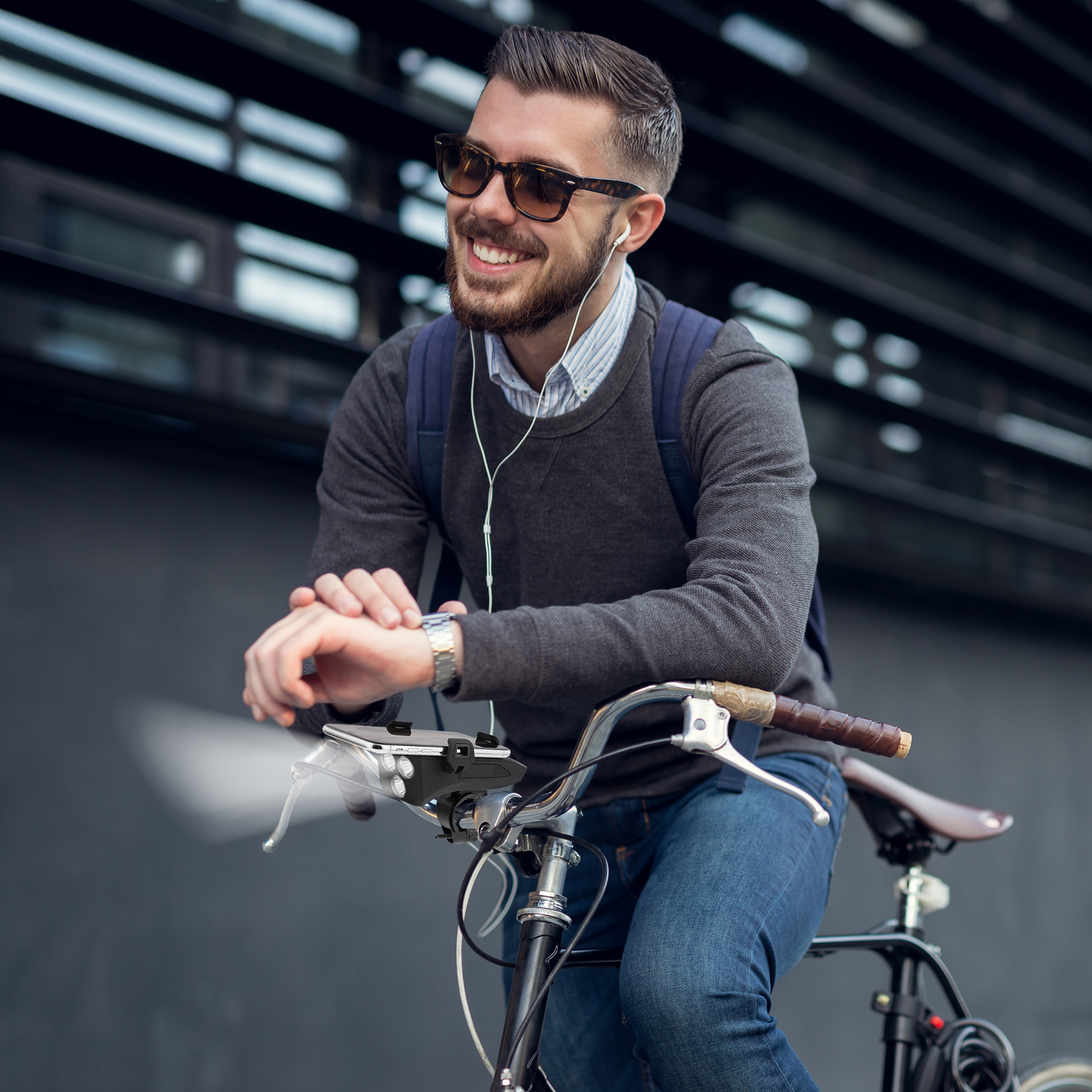 Een man op een fiets draagt een zonnebril en oortelefoons. Hij kijkt naar zijn horloge, glimlacht en houdt de fiets vast.