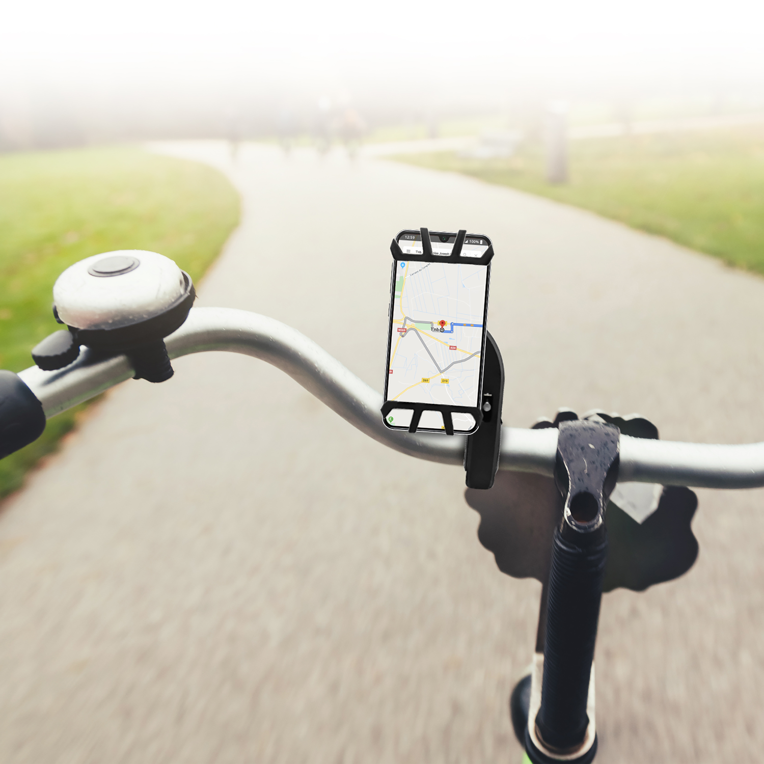 Bike handlebars with phone mount, displaying a map, on a paved path in a park.