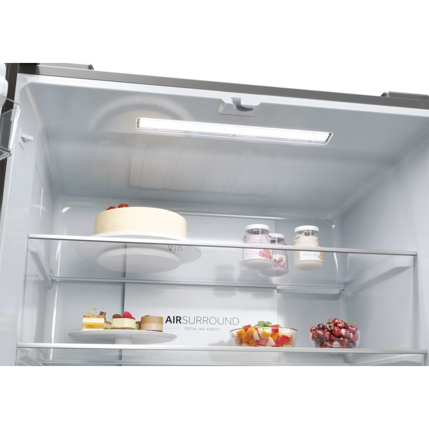 Interno del frigorifero con torta, yogurt e frutta. Una luce è sopra i ripiani.