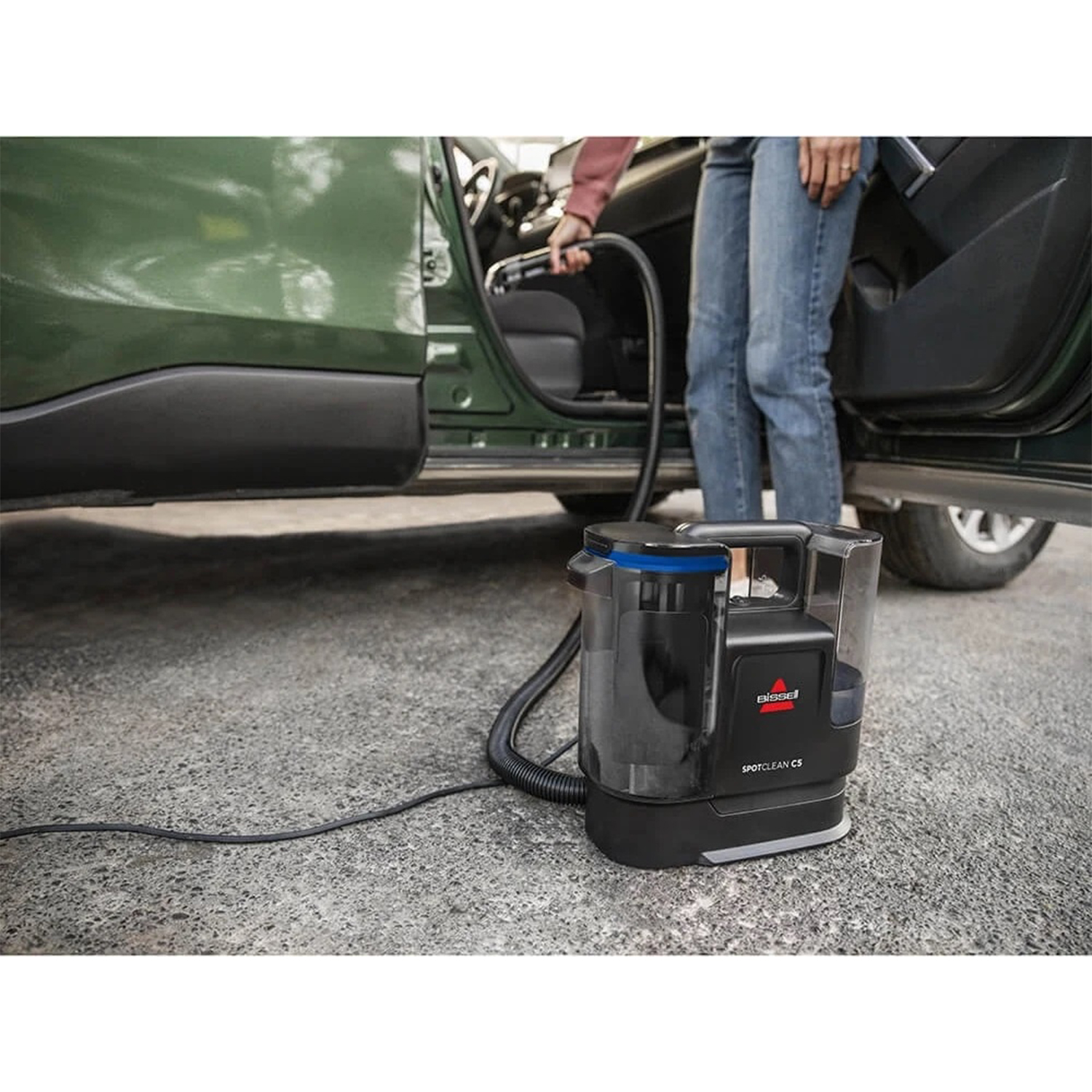 Persona che utilizza un aspirapolvere Bissell SpotClean C5 all'interno di un'auto.