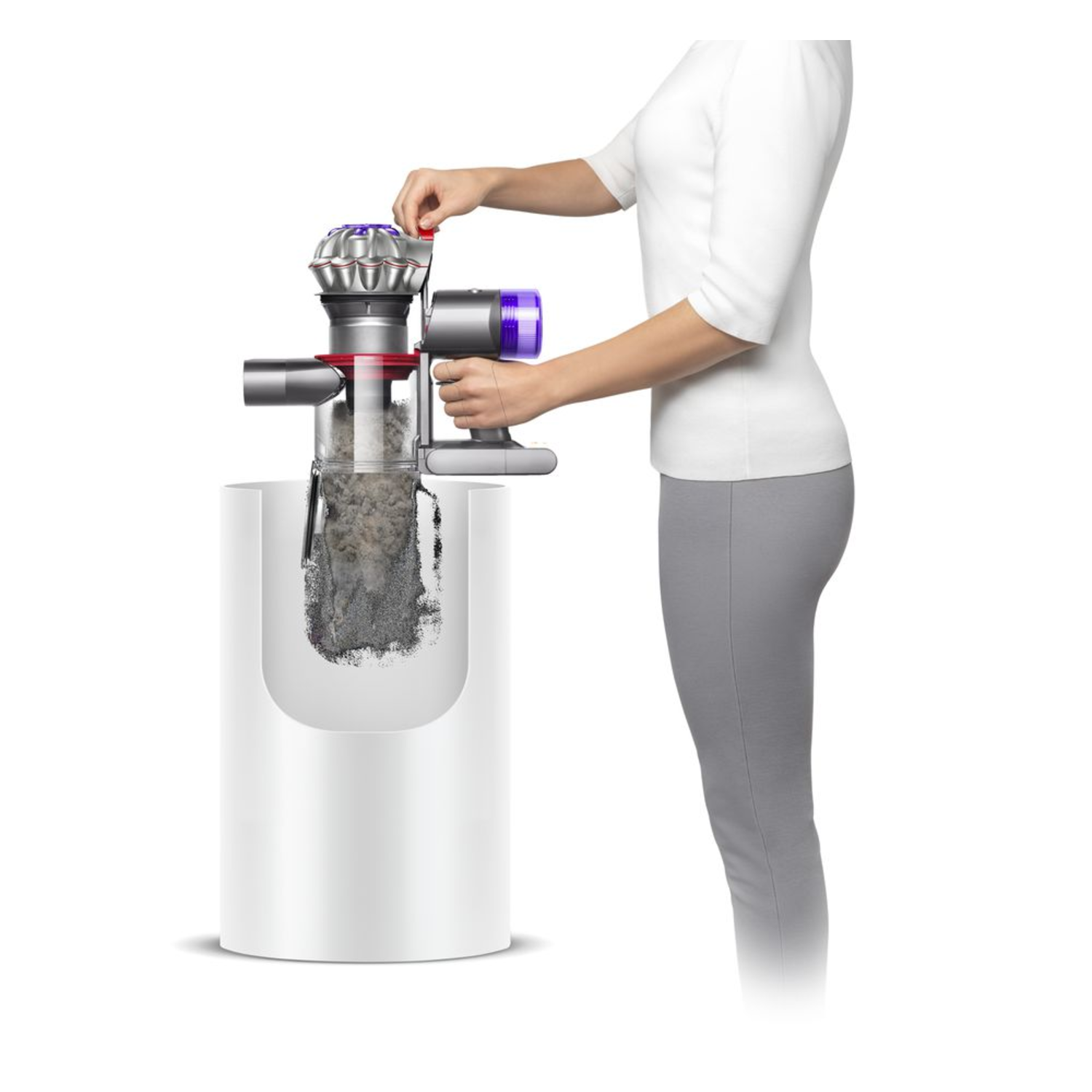 Een vrouw die een Dyson-stofzuiger leegt in een witte bak. De bak en de stofzuiger zijn wit.